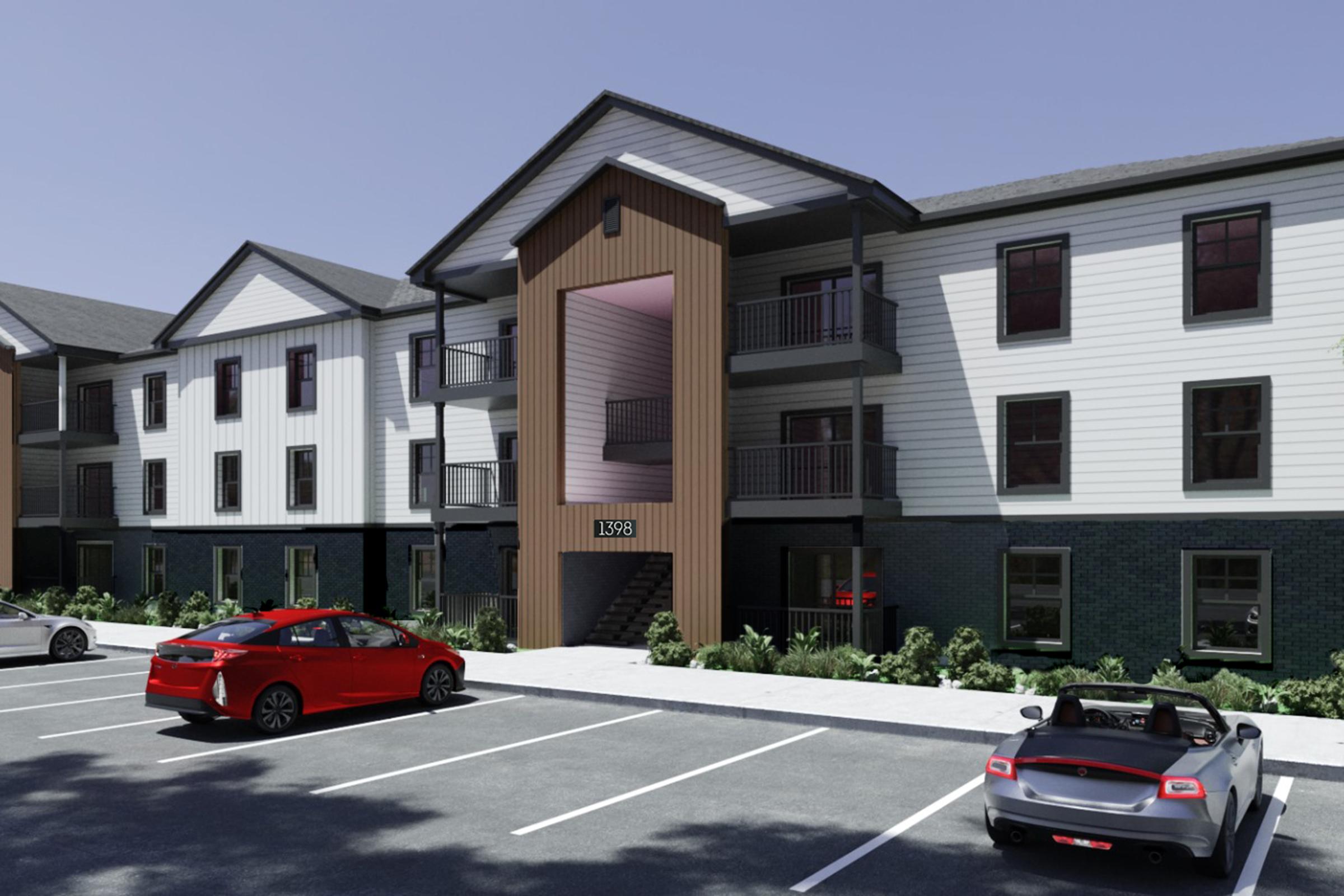 A modern multi-story apartment building with a welcoming entrance. The exterior features a combination of white and dark-colored siding, large windows, and landscaped greenery. There's a parking lot in front with several cars parked, including a red sedan and a black convertible.