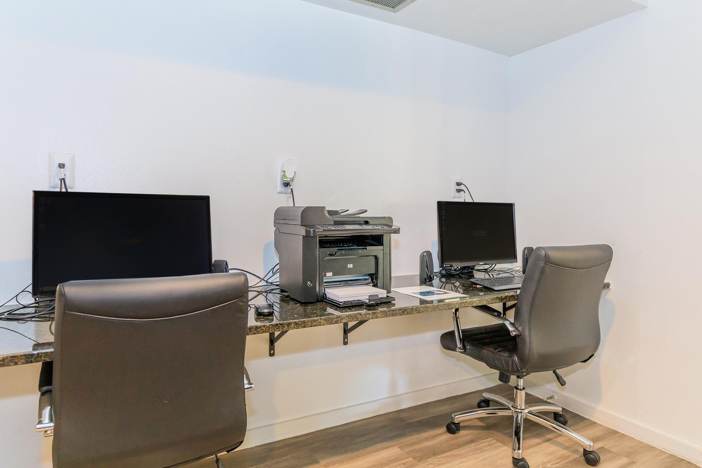 a desk with a computer and a chair in a room