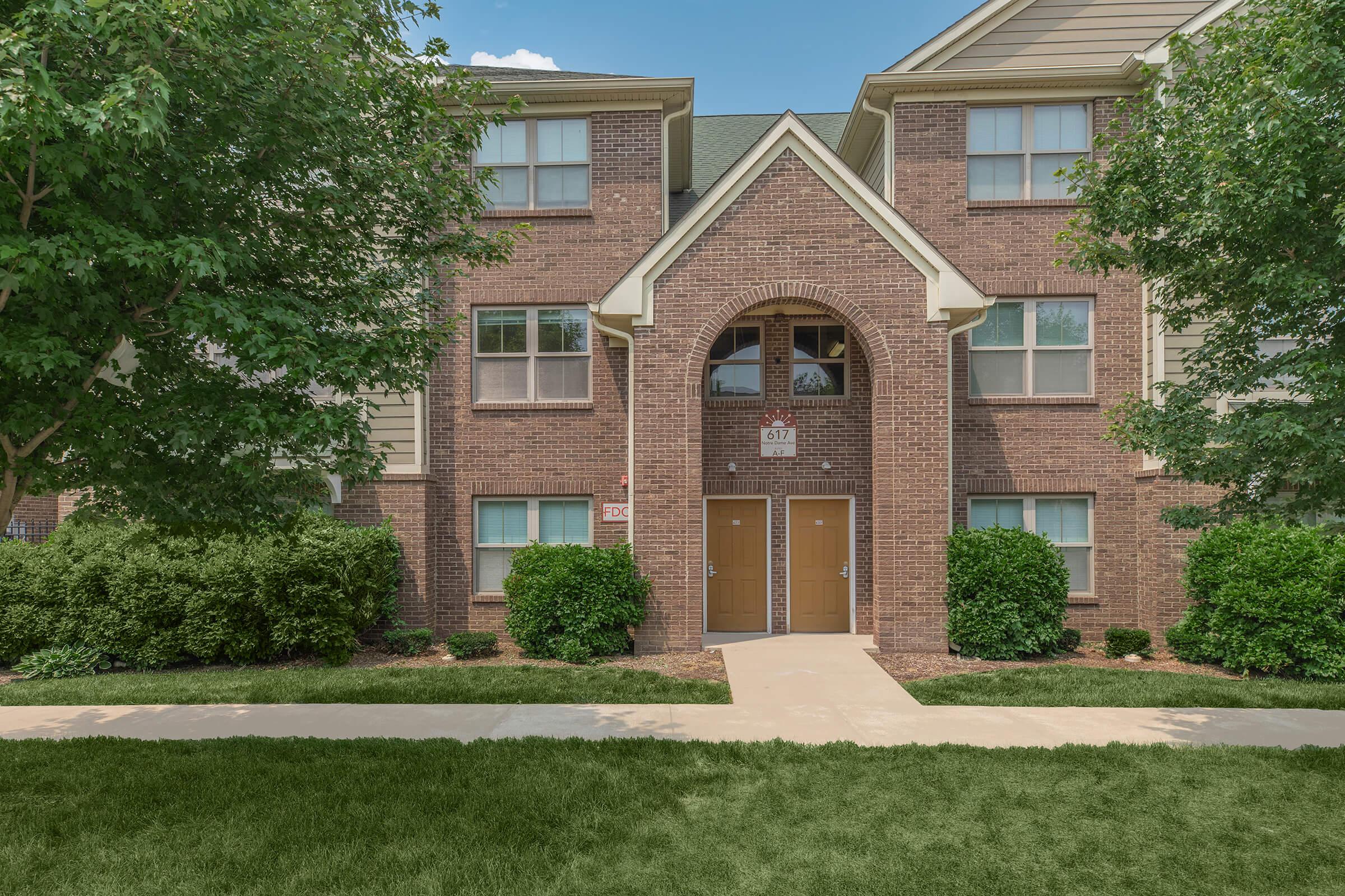 a house with a lawn in front of a brick building