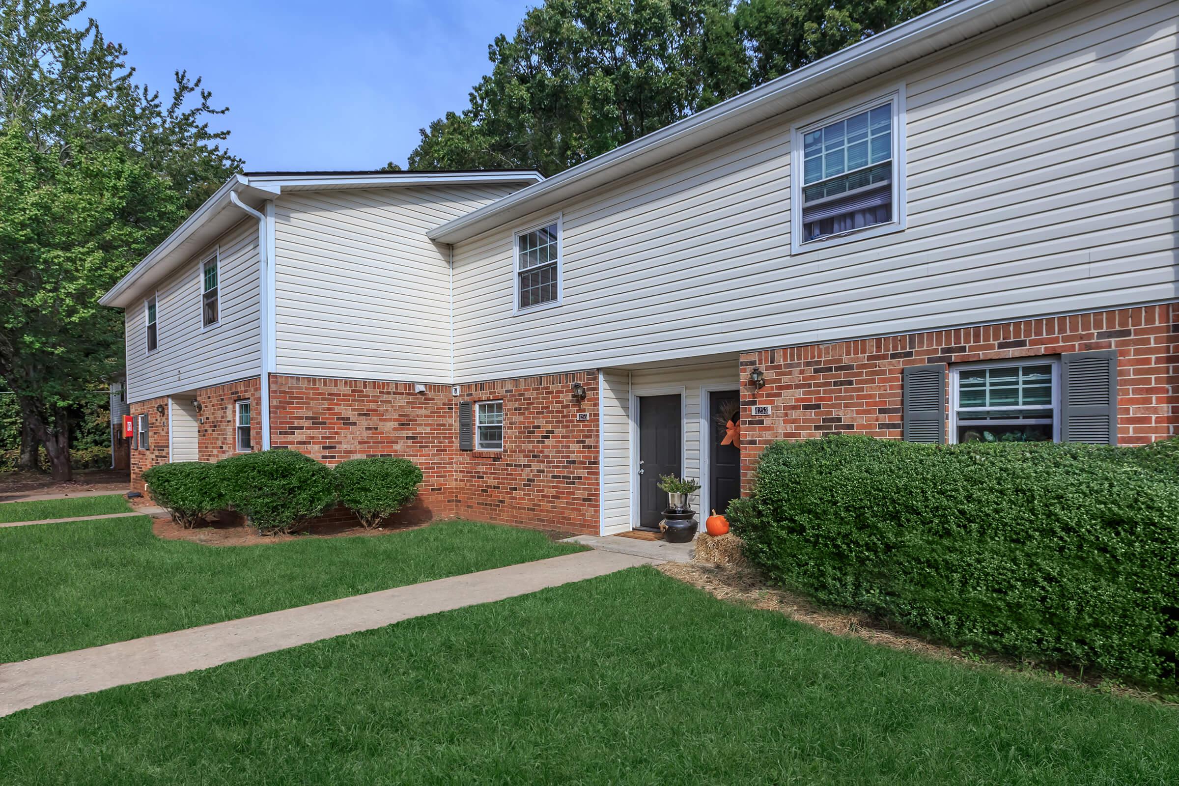 a house with a lawn in front of a brick building