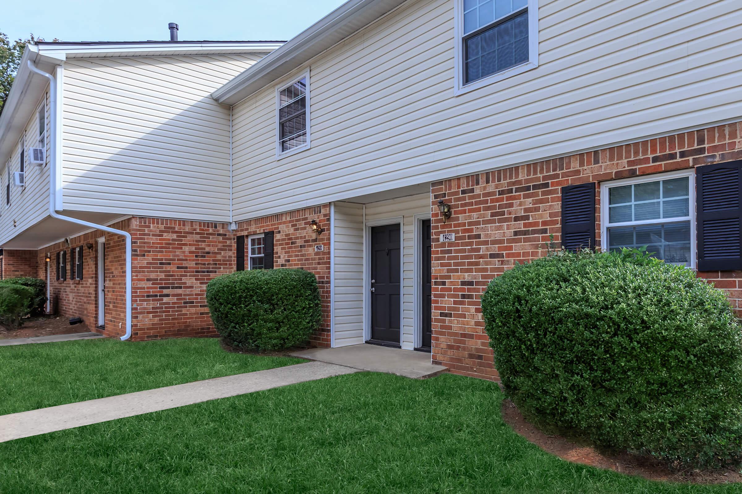 a house with a lawn in front of a brick building