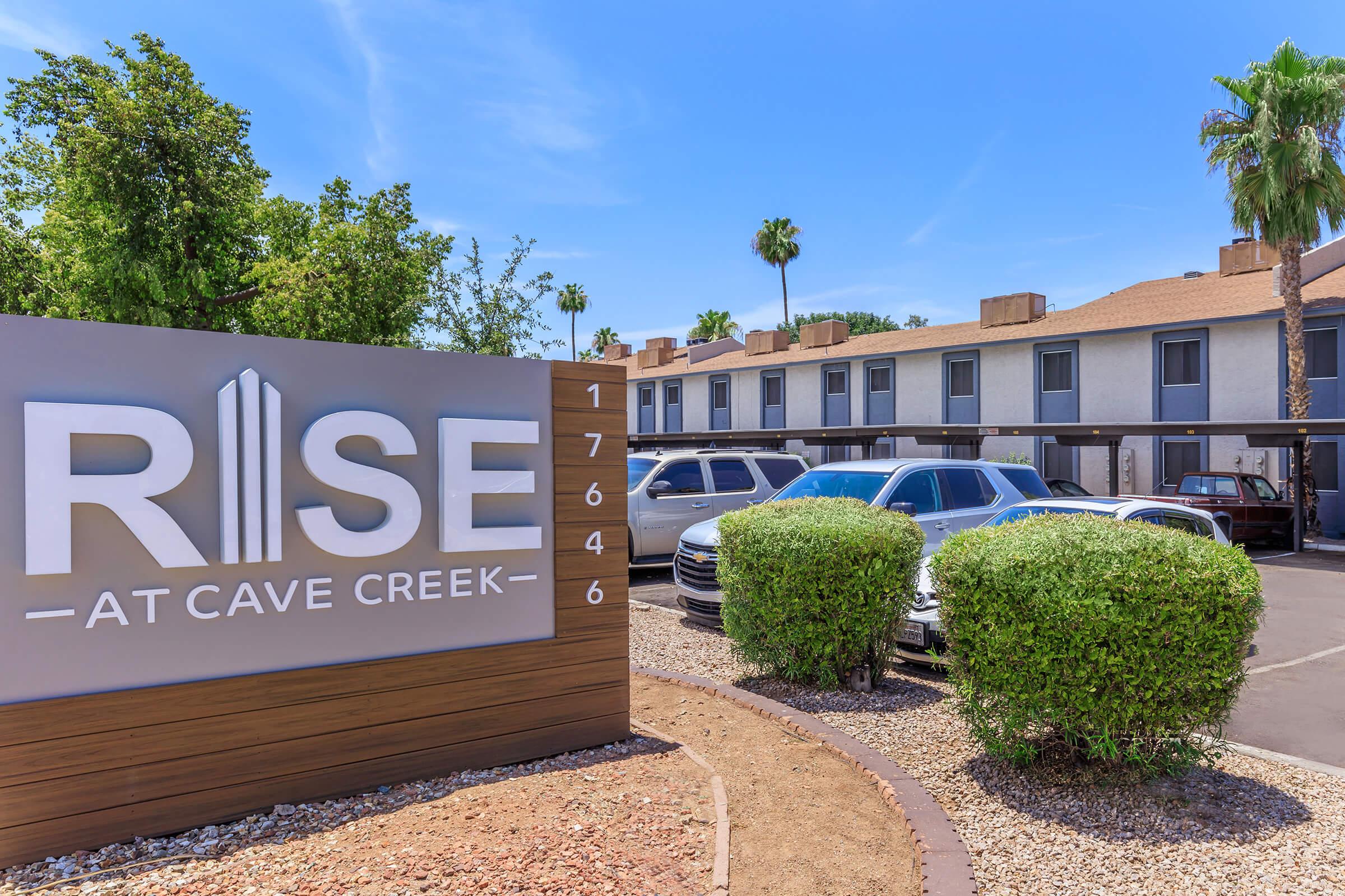 Side view of Rise at Cave Creek signage in front of large apartment complex and parking lot in Phoenix, AZ