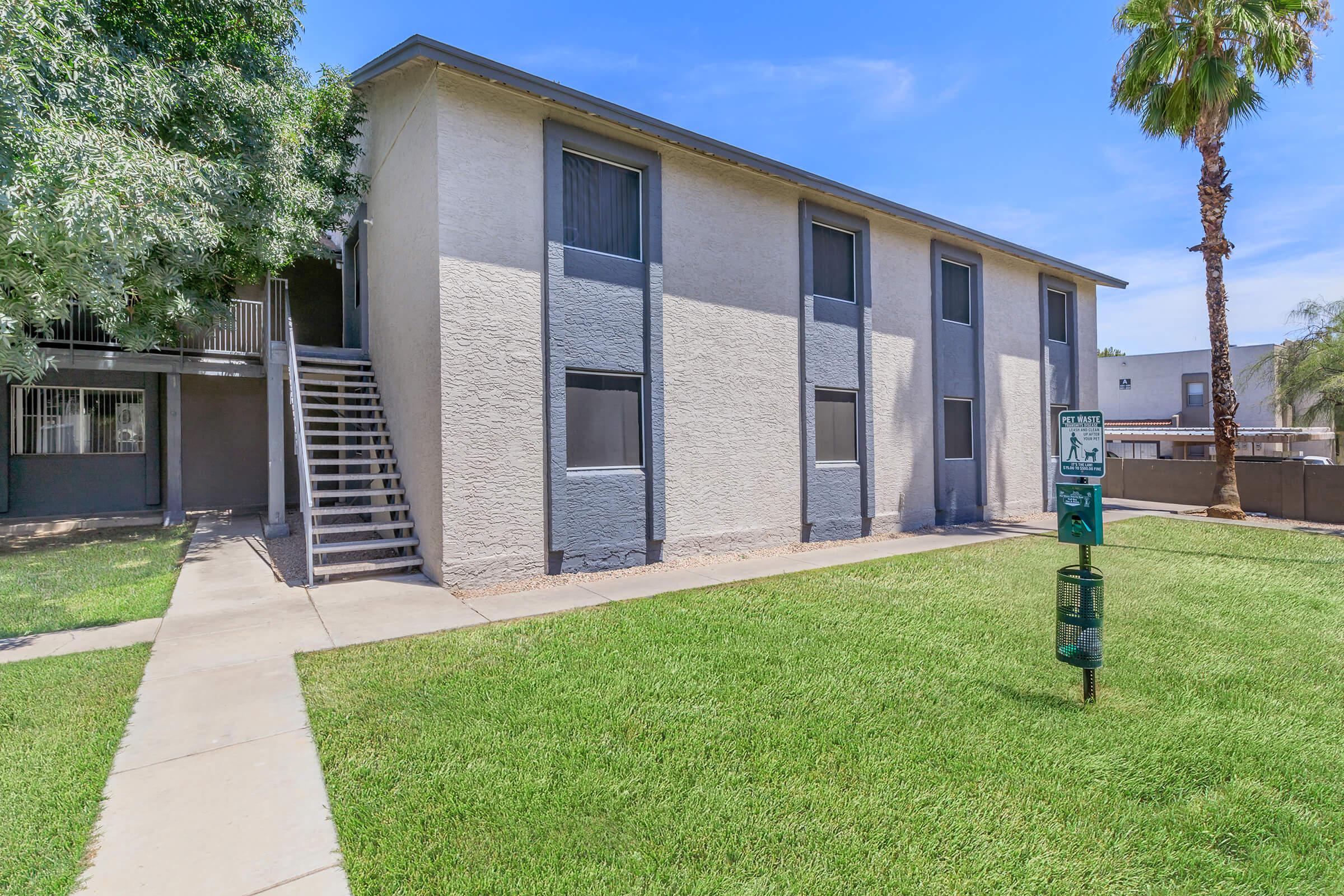Two-story Phoenix apartments for rent with large grassy lot and dog clean up station in front