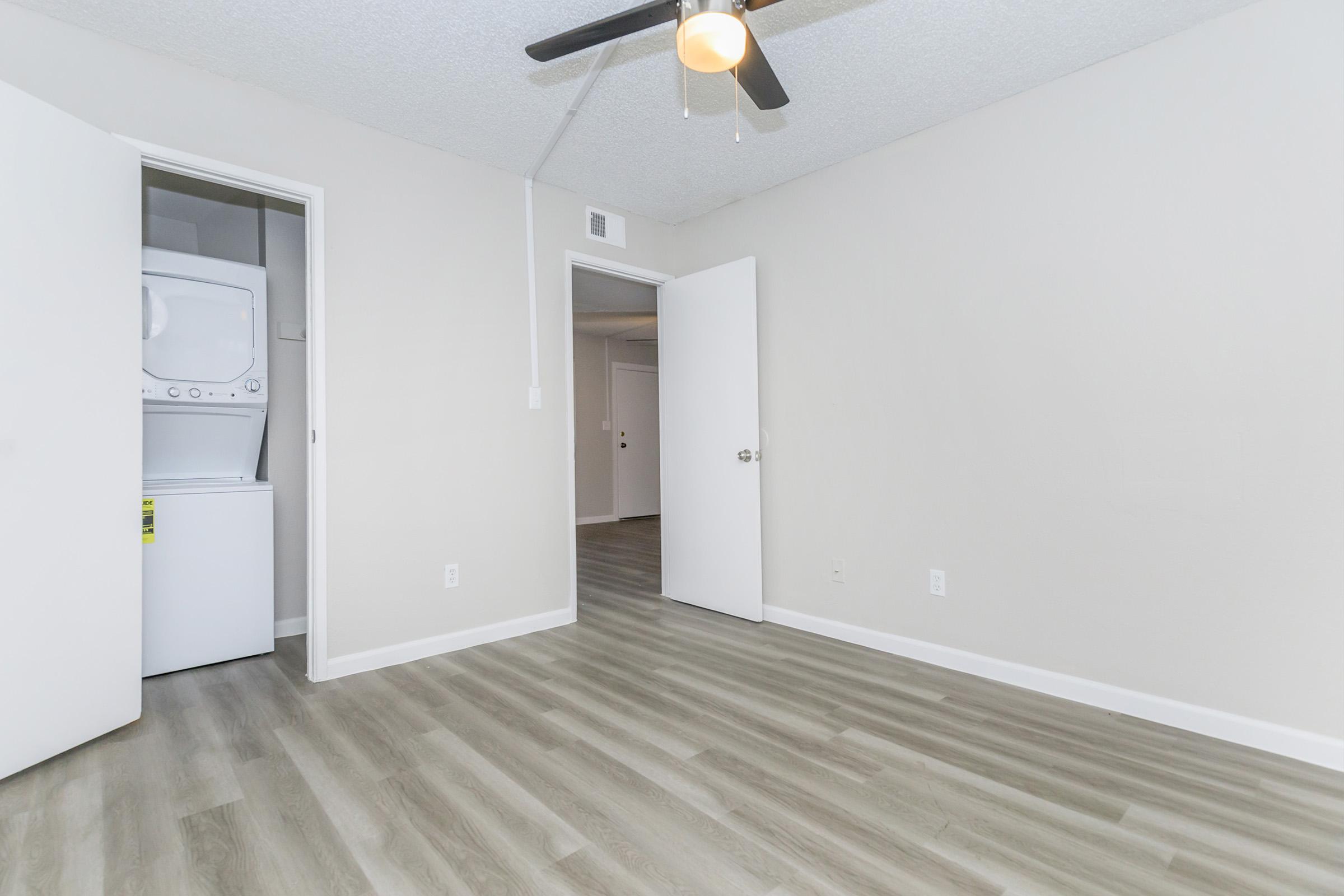 Spacious renovated bedroom with ceiling fan and washer and dryer in closet