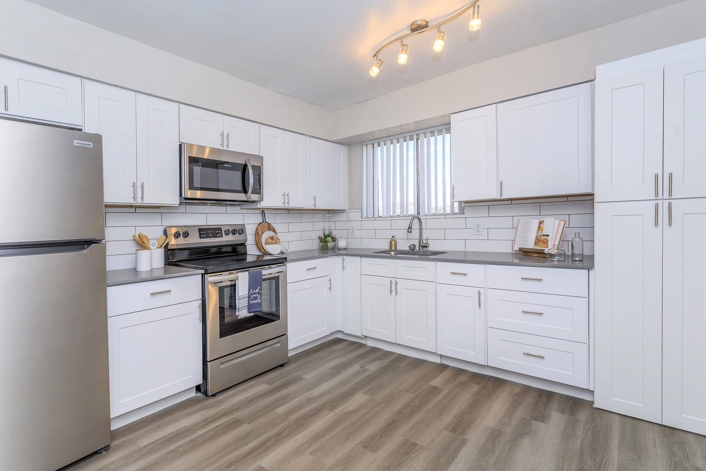 Large modern renovated Phoenix apartment kitchen with white cabinets and stainless steel appliances 