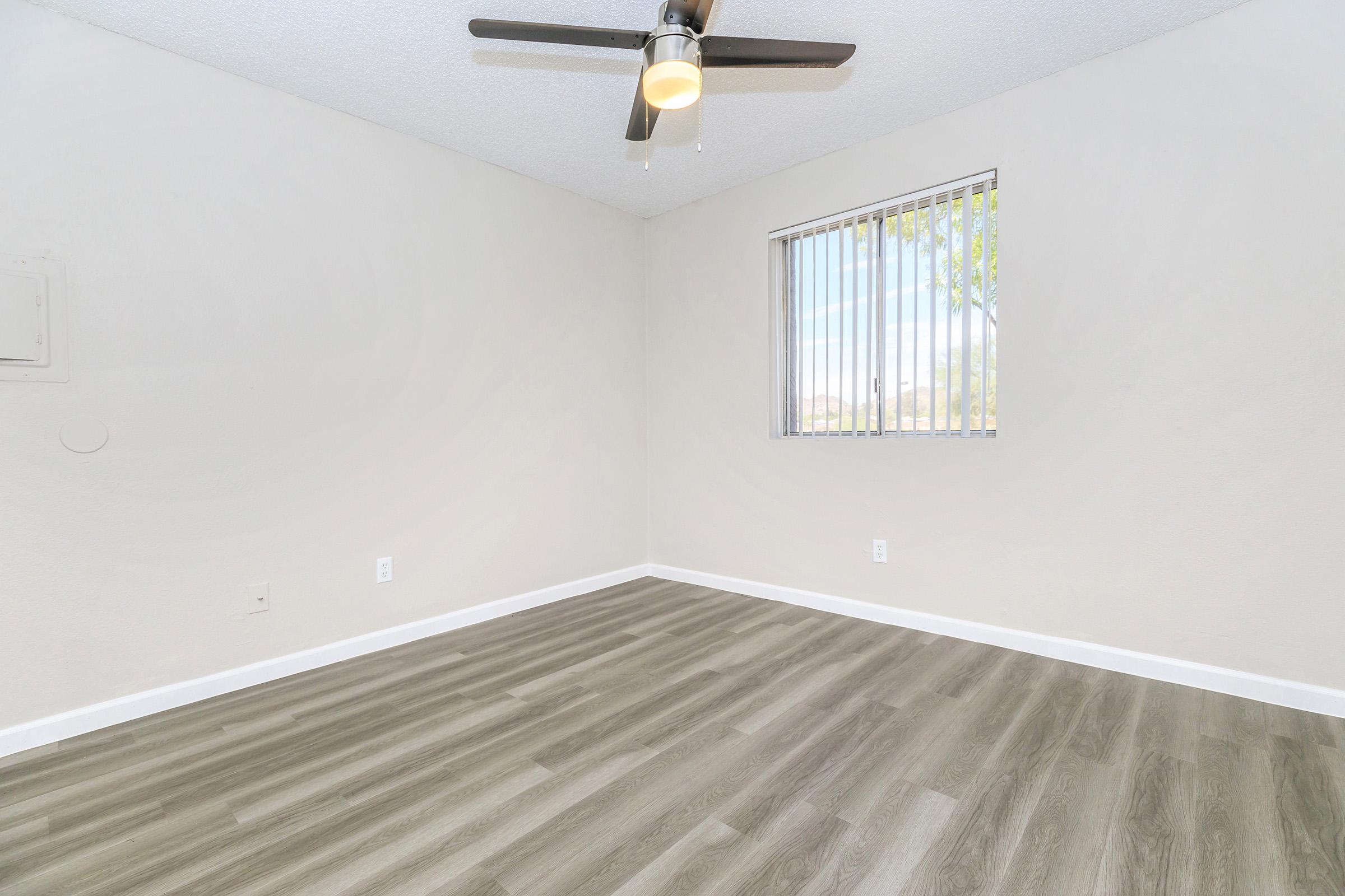 Spacious renovated empty Phoenix apartment bedroom with window and fan 