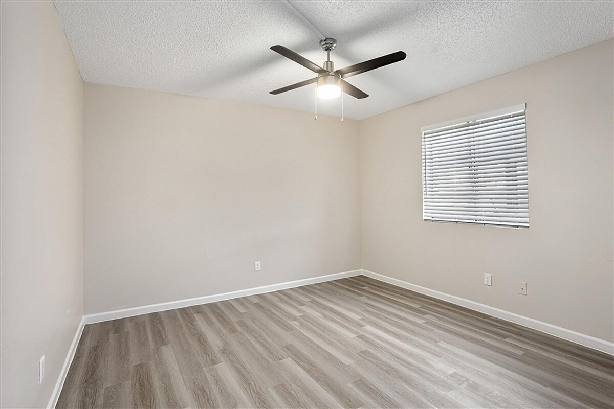 Modern renovated bedroom with vinyl flooring, window, and ceiling fan