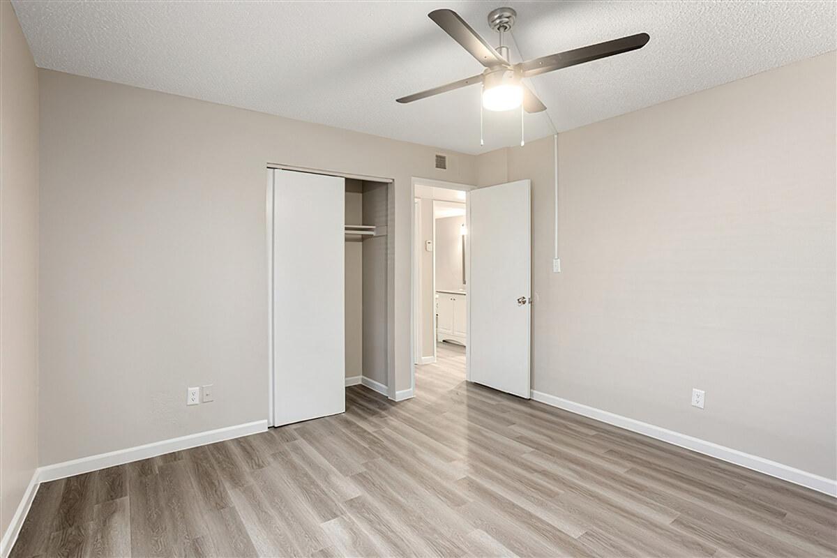 Modern bedroom space with ceiling fan and closet