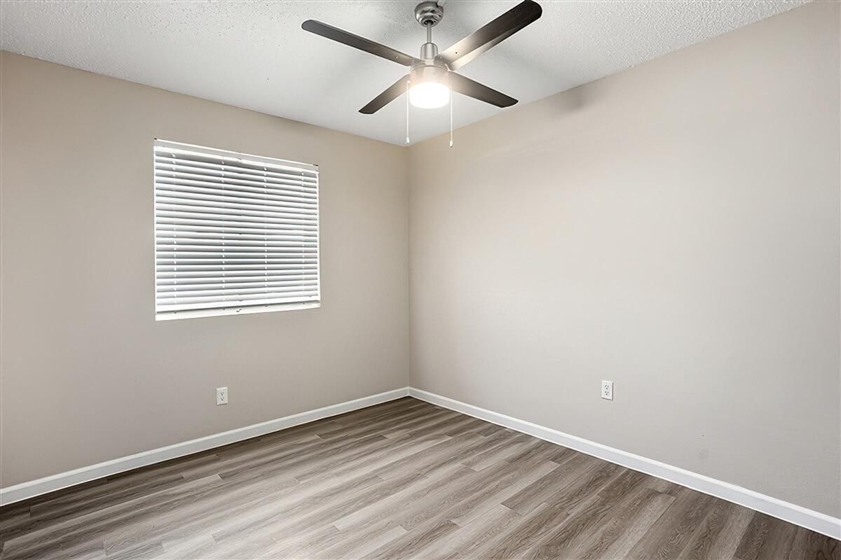 Modern renovated bedroom with vinyl flooring, window, and ceiling fan