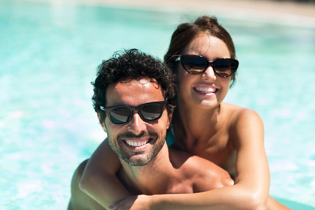 a person wearing sunglasses and standing next to a body of water