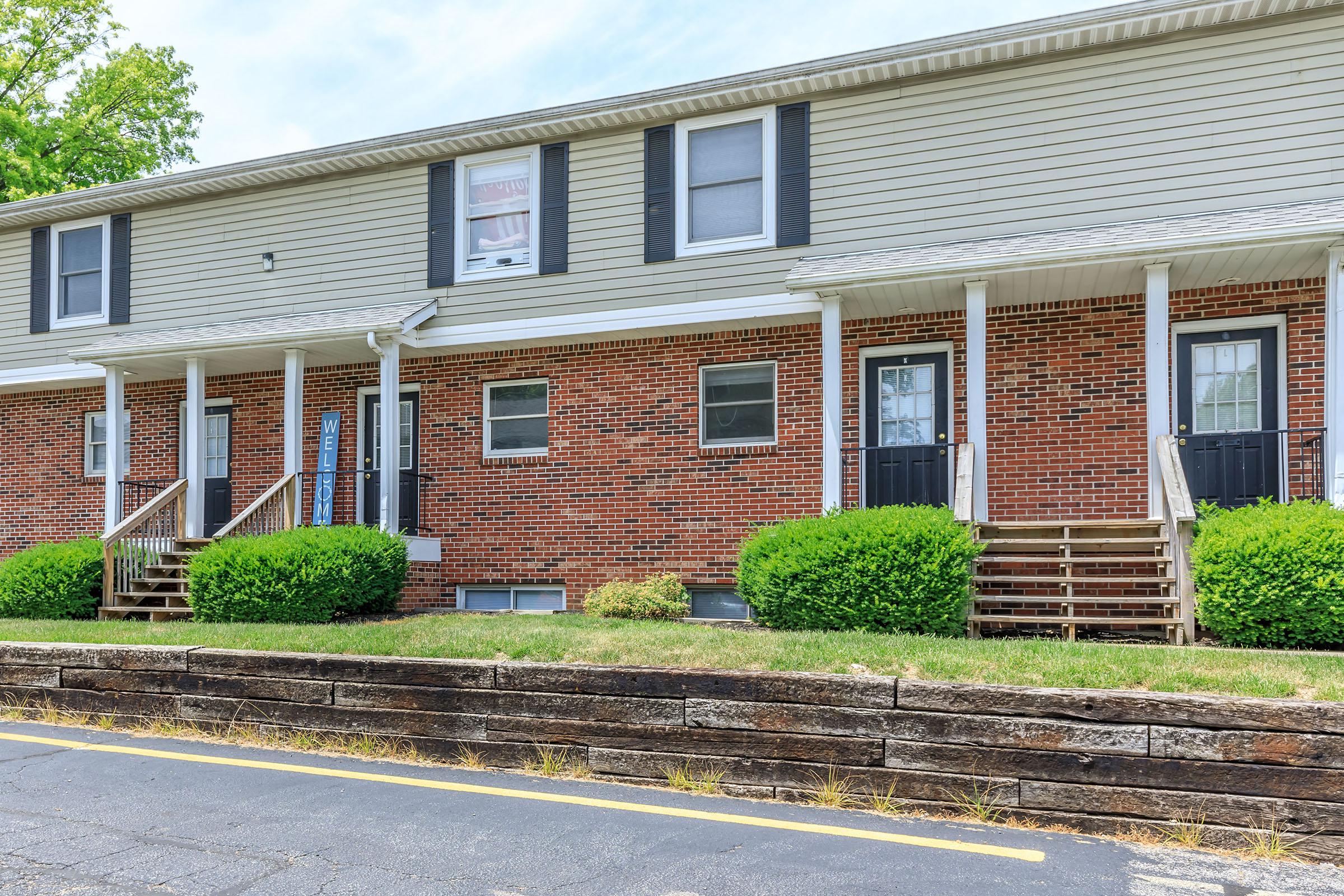 a large brick building with grass in front of a house