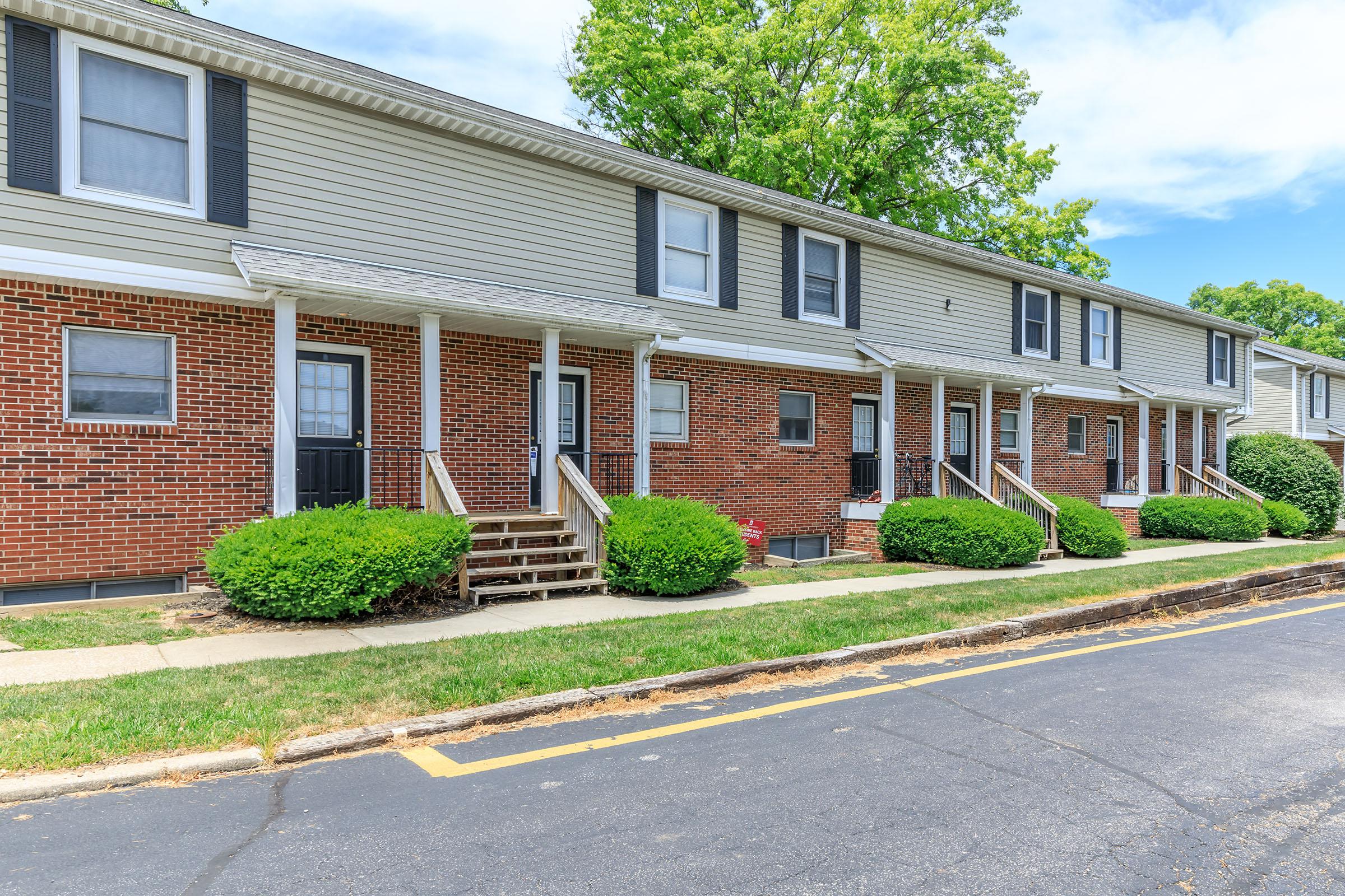 a large brick building with grass in front of a house