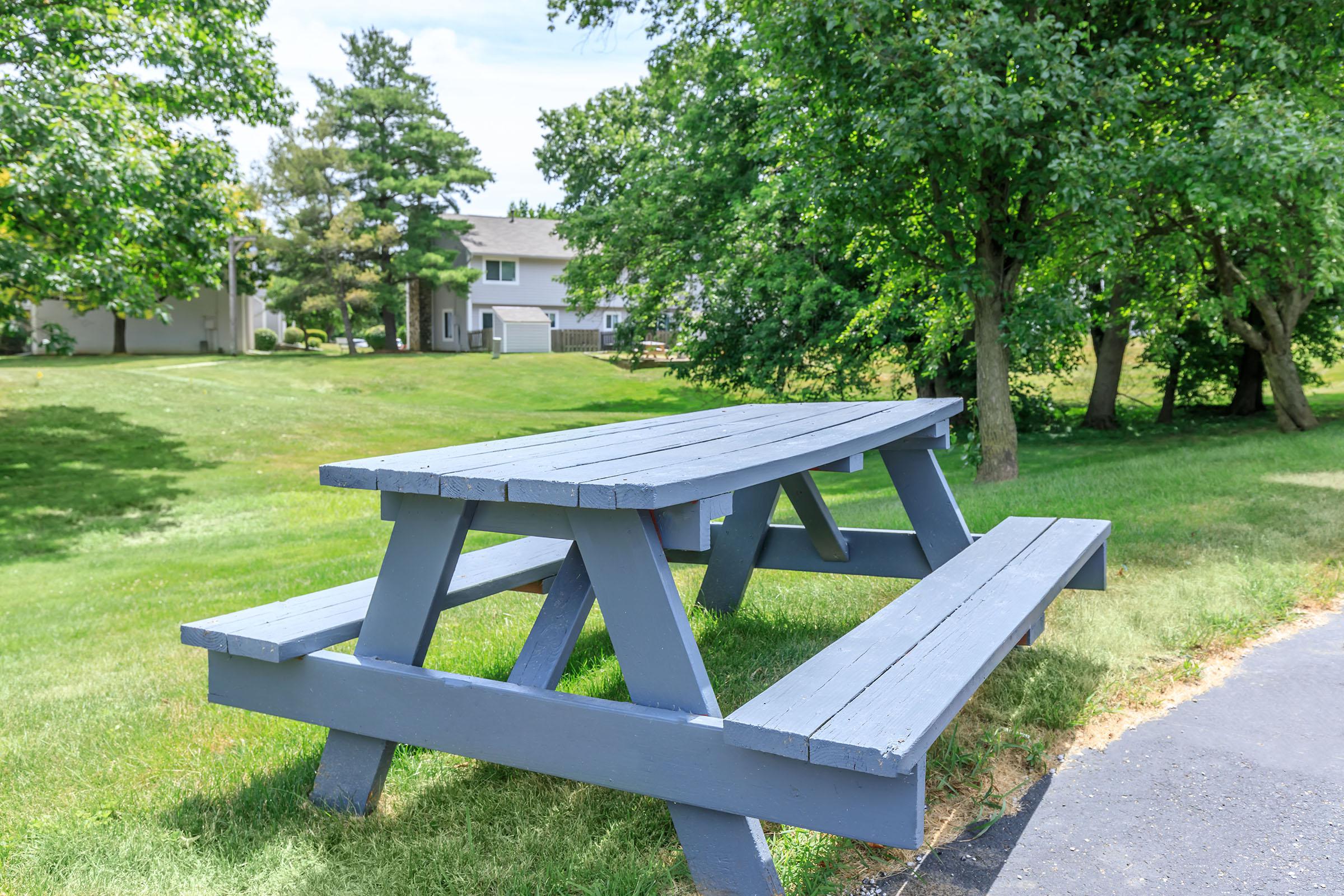 an empty park bench sitting in the grass