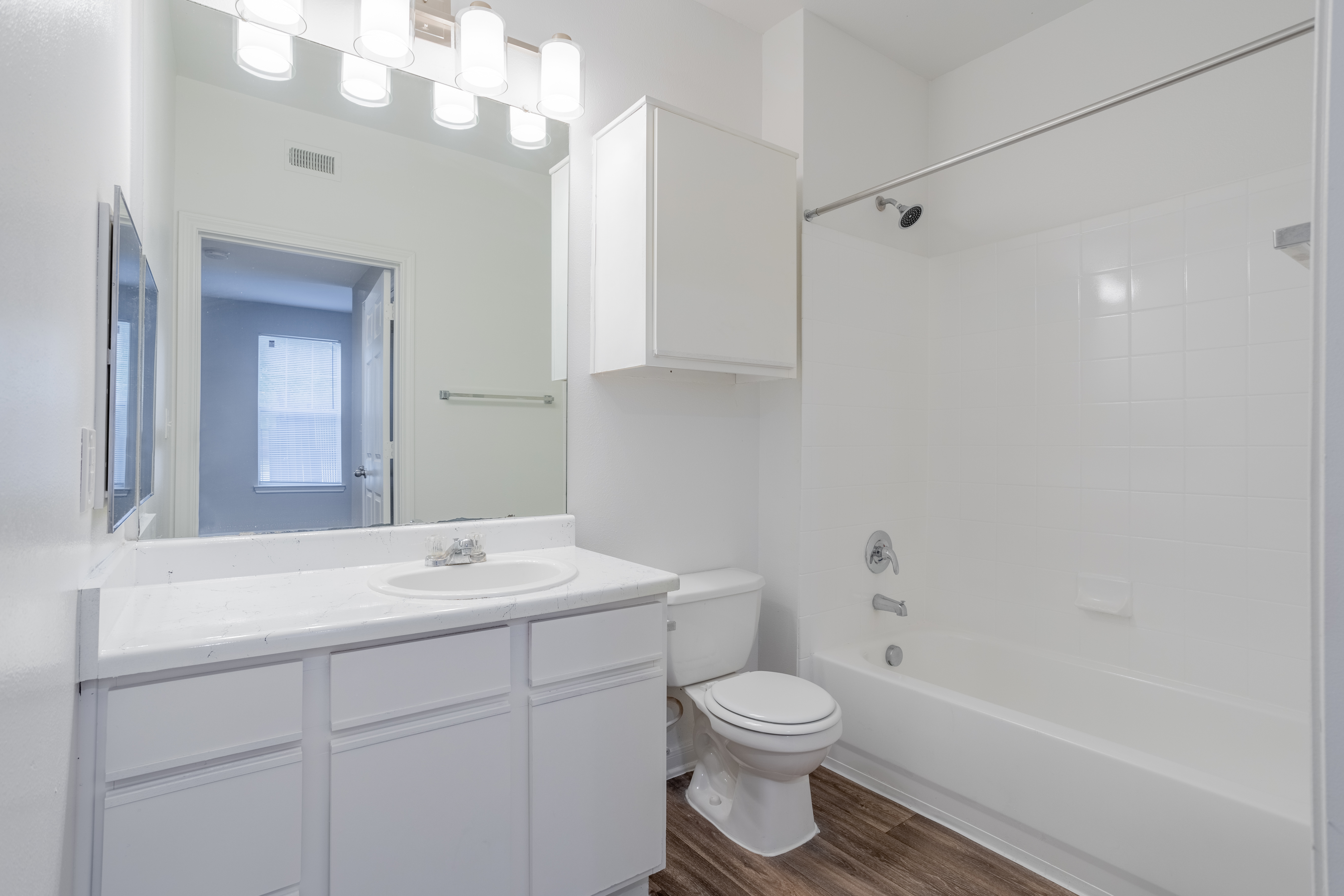 North Forest Trails Apts Houston 1 bedroom apartment bathroom with white cabinets and wood like floo