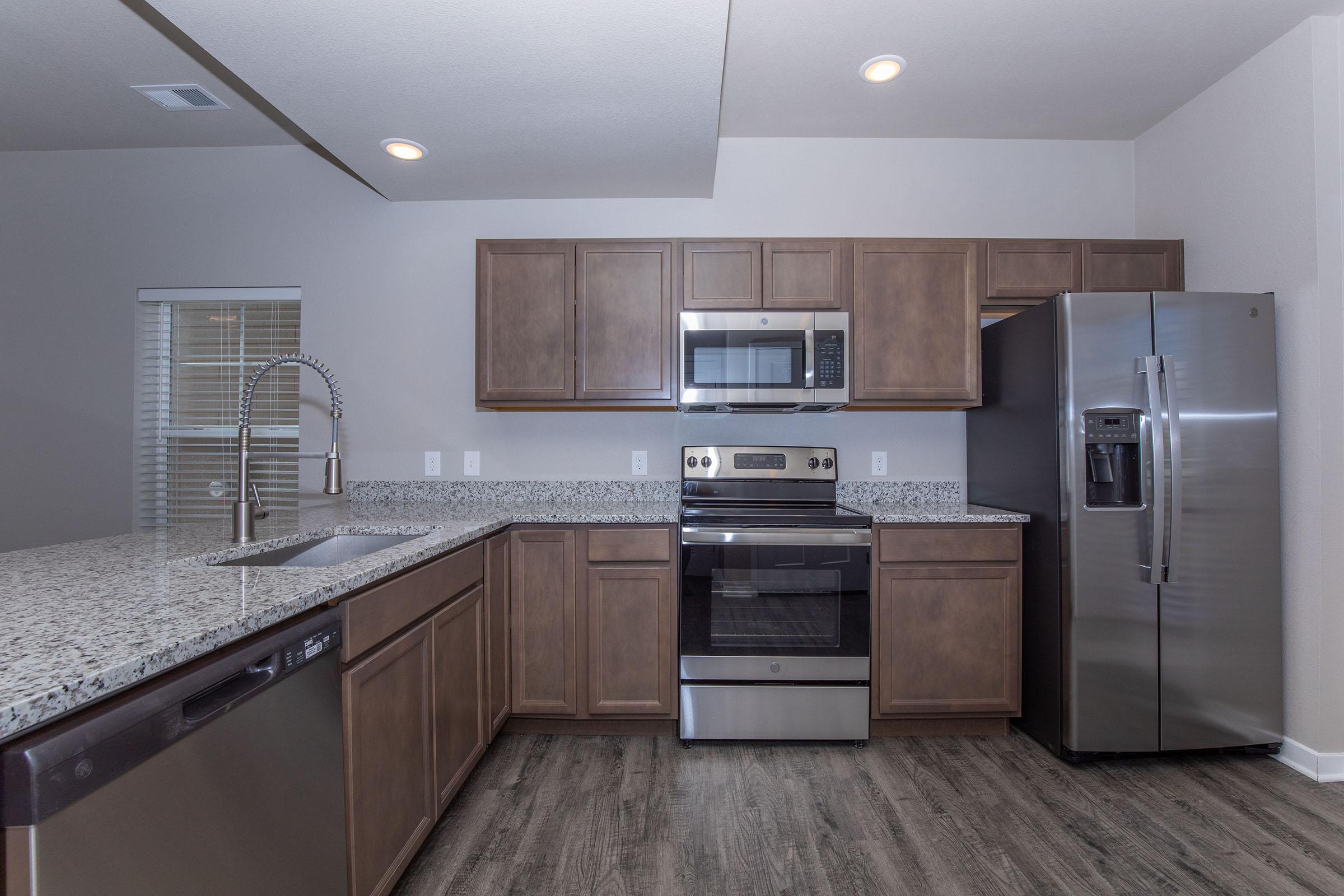 a large kitchen with stainless steel appliances and wooden cabinets