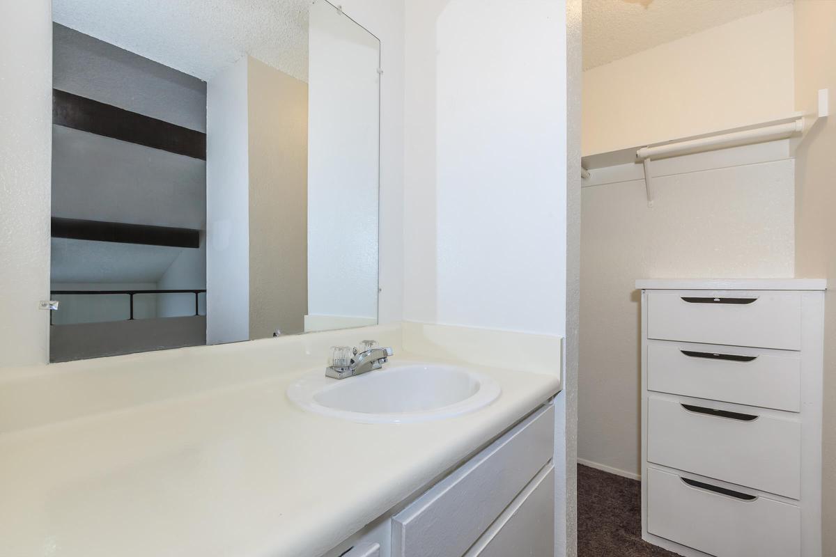 a white sink sitting under a mirror