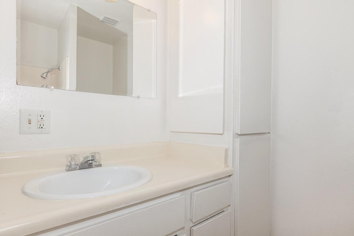 a white sink sitting under a mirror