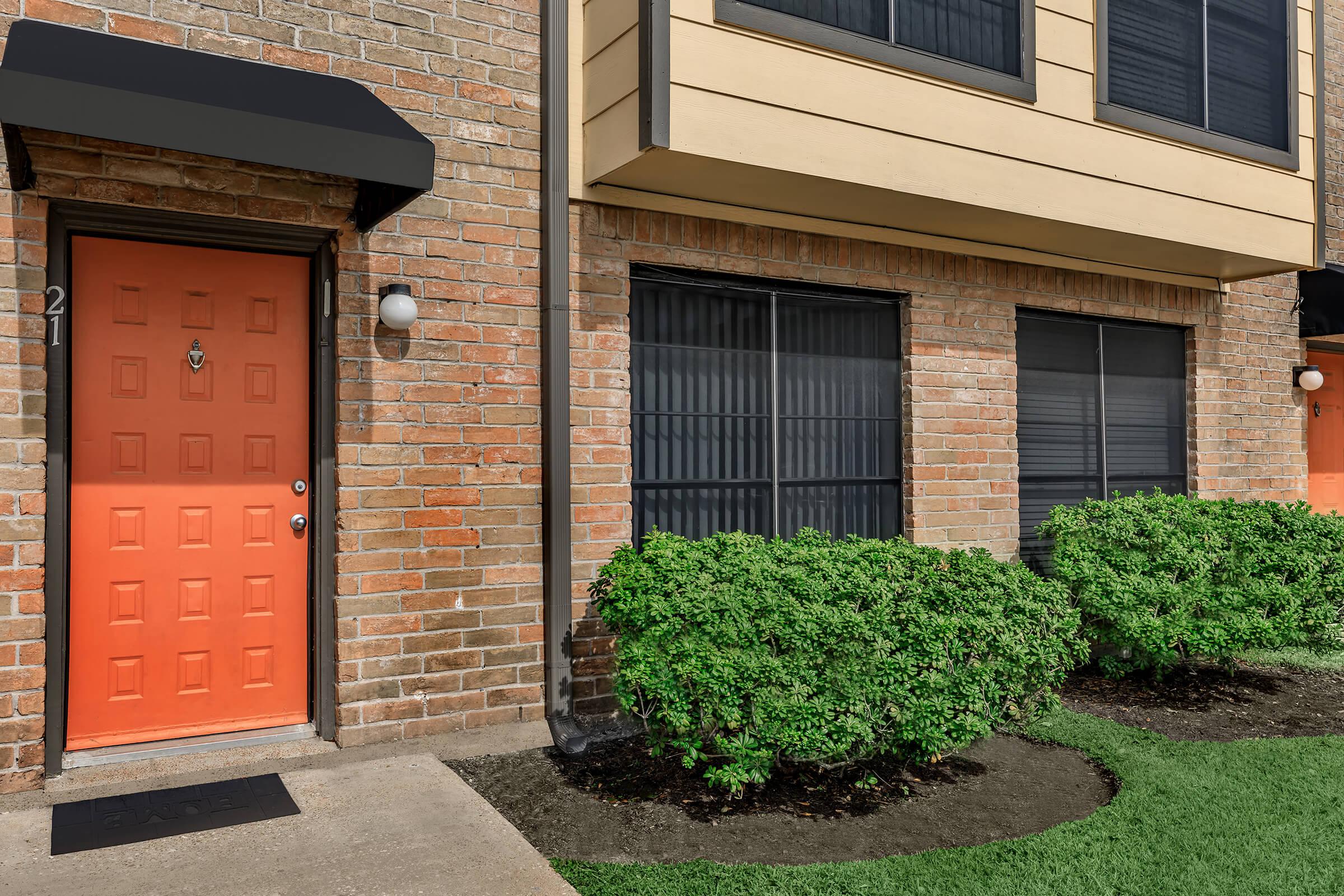 a house with bushes in front of a brick building