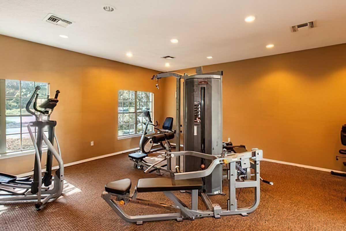 A modern gym interior featuring various exercise equipment, including a multi-gym machine, stationary bike, and elliptical.