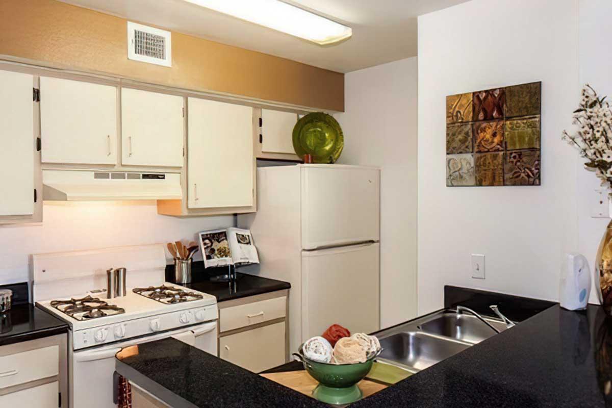 A modern kitchen featuring white cabinets, a gas stove, and a refrigerator.