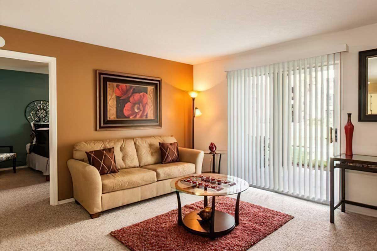 Cozy living room featuring a beige sofa with decorative pillows, a round coffee table with a centerpiece, and a light brown area rug.