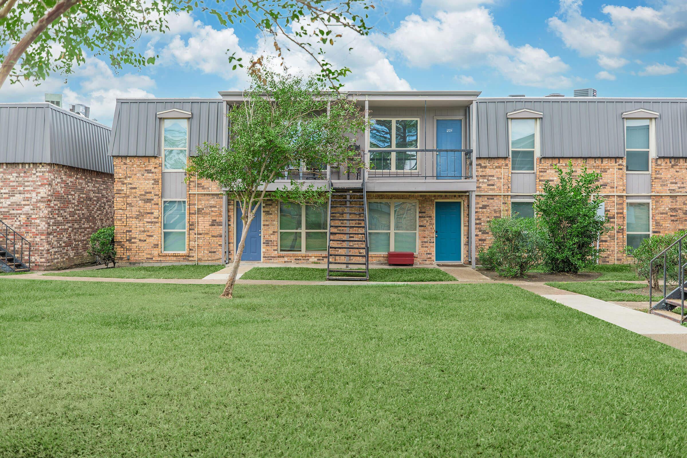 a large brick building with green grass in front of a house