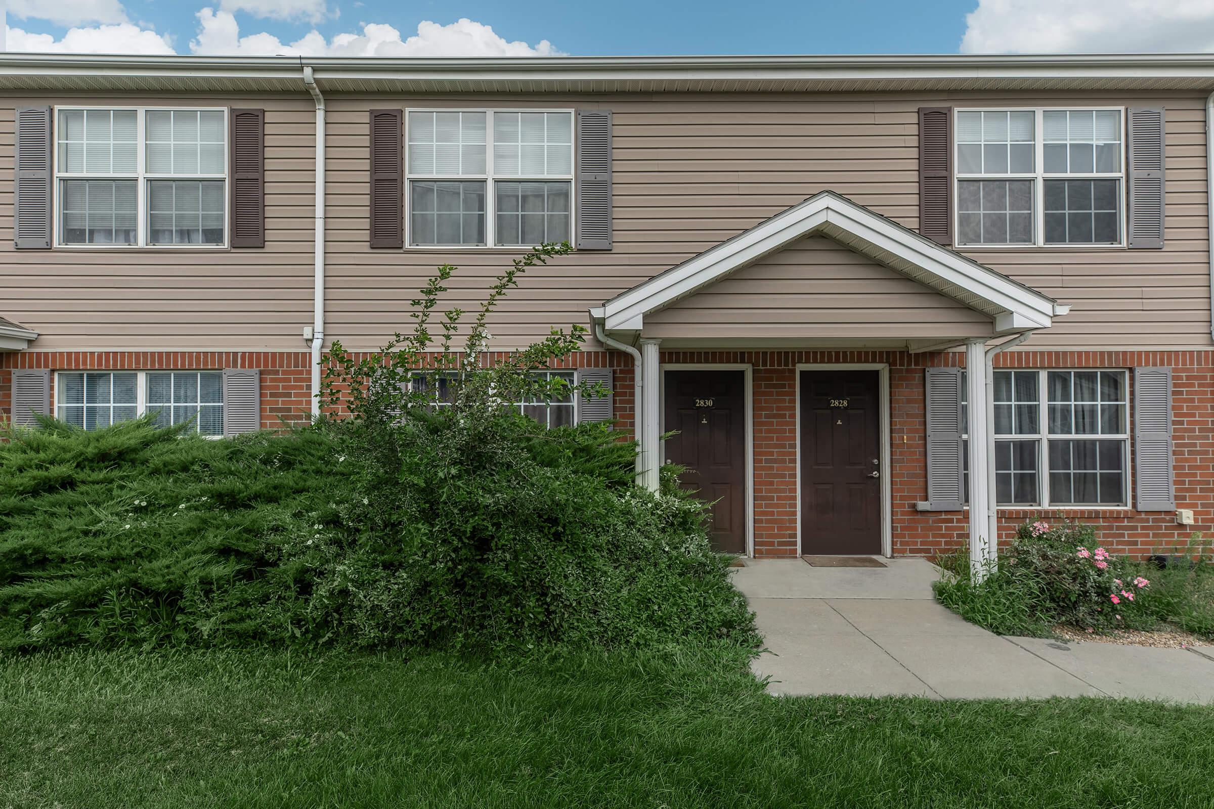 a large brick building with grass in front of a house