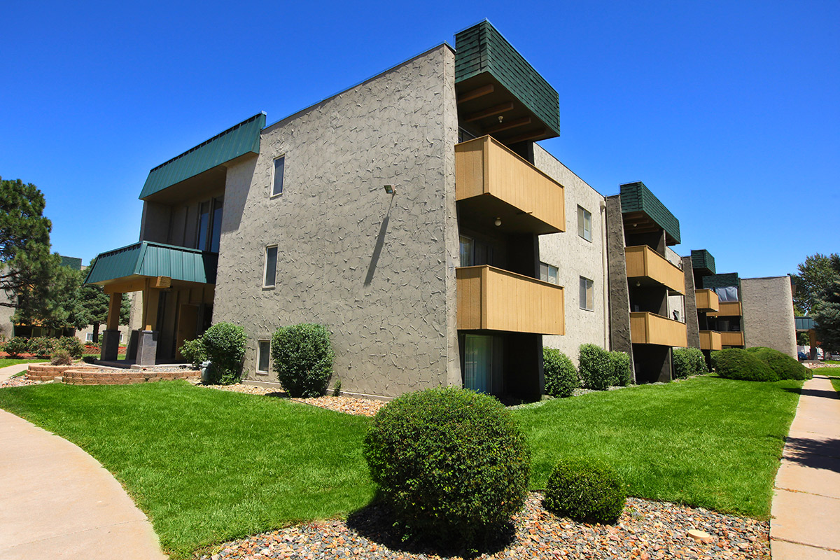 a large brick building with grass in front of a house