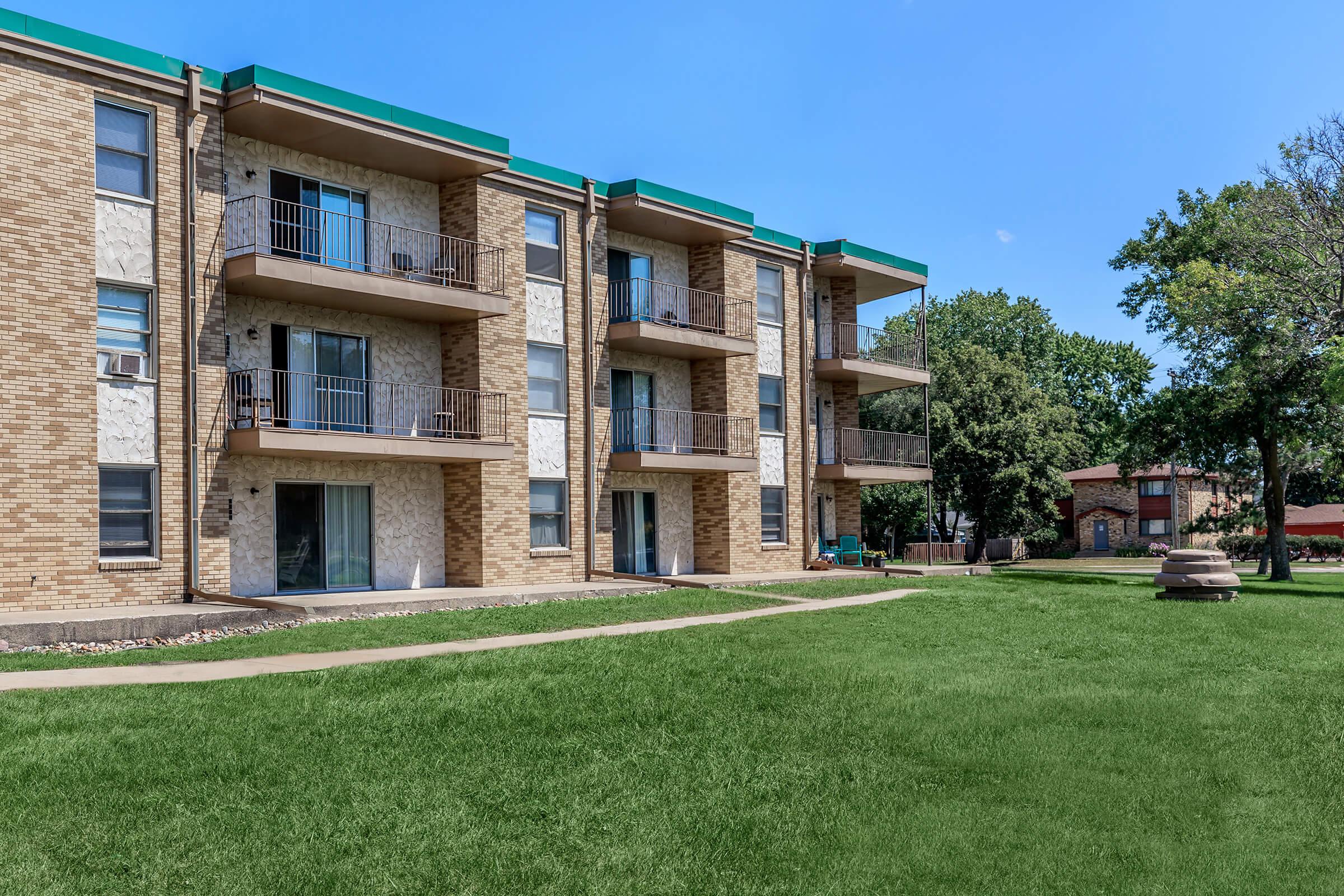 a large brick building with green grass in front of a house