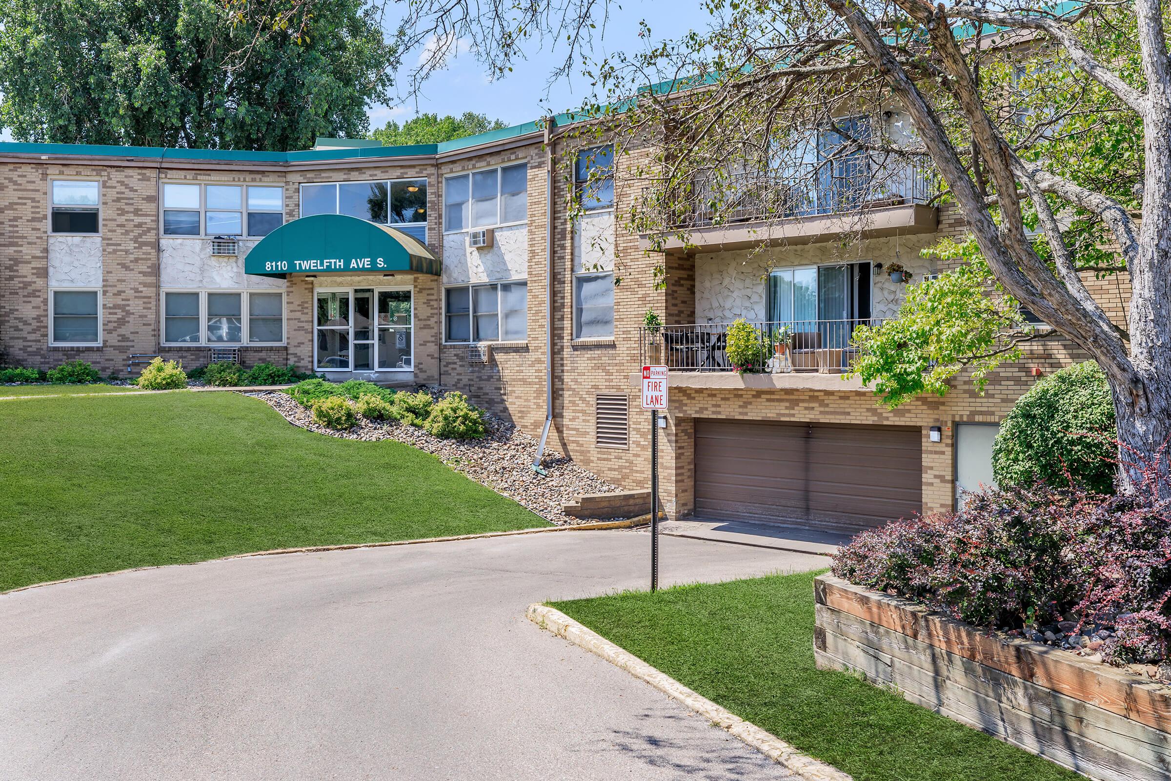 a large brick building with grass in front of a house