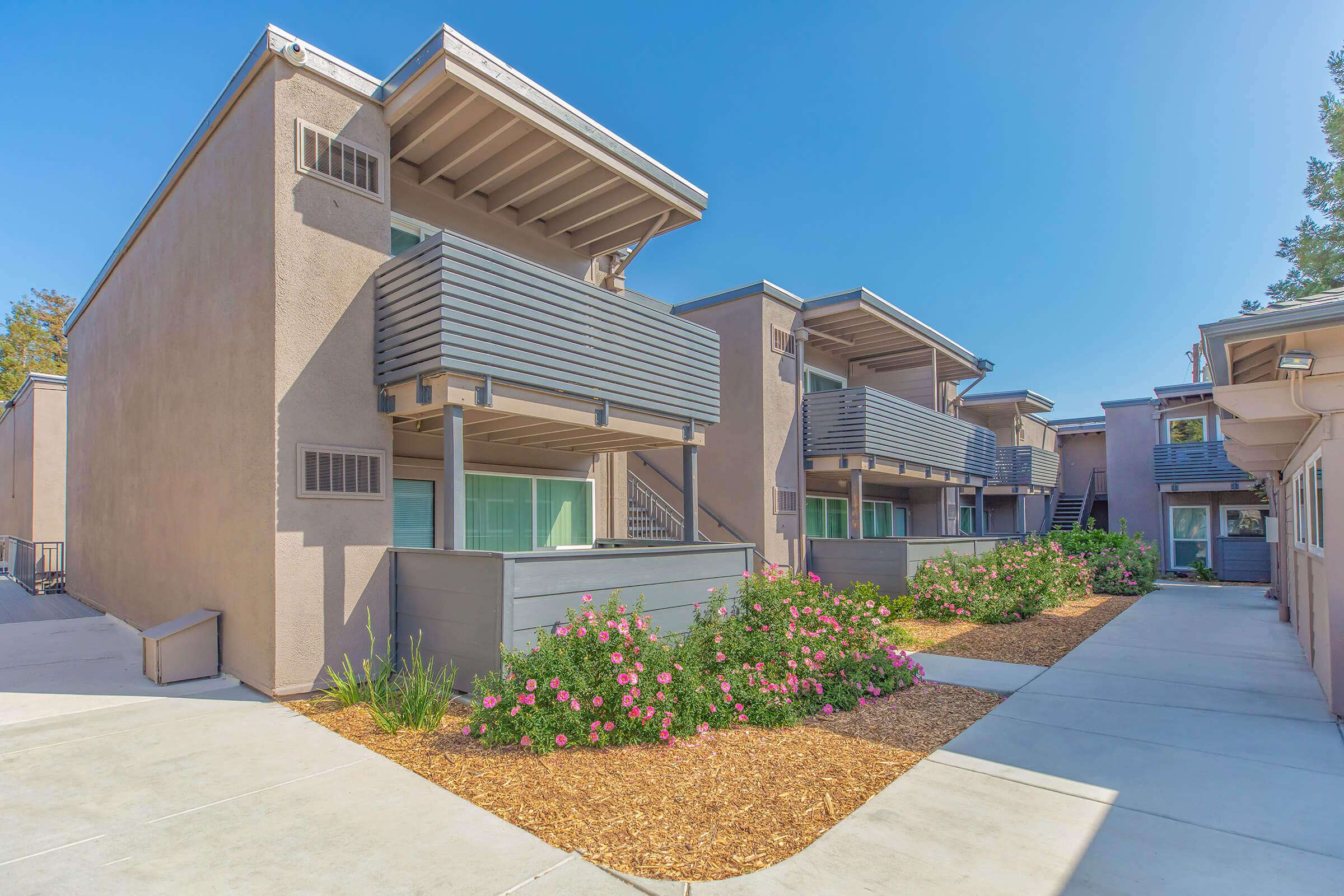 Two-story apartment building with beautiful landscaping and concrete walkways.