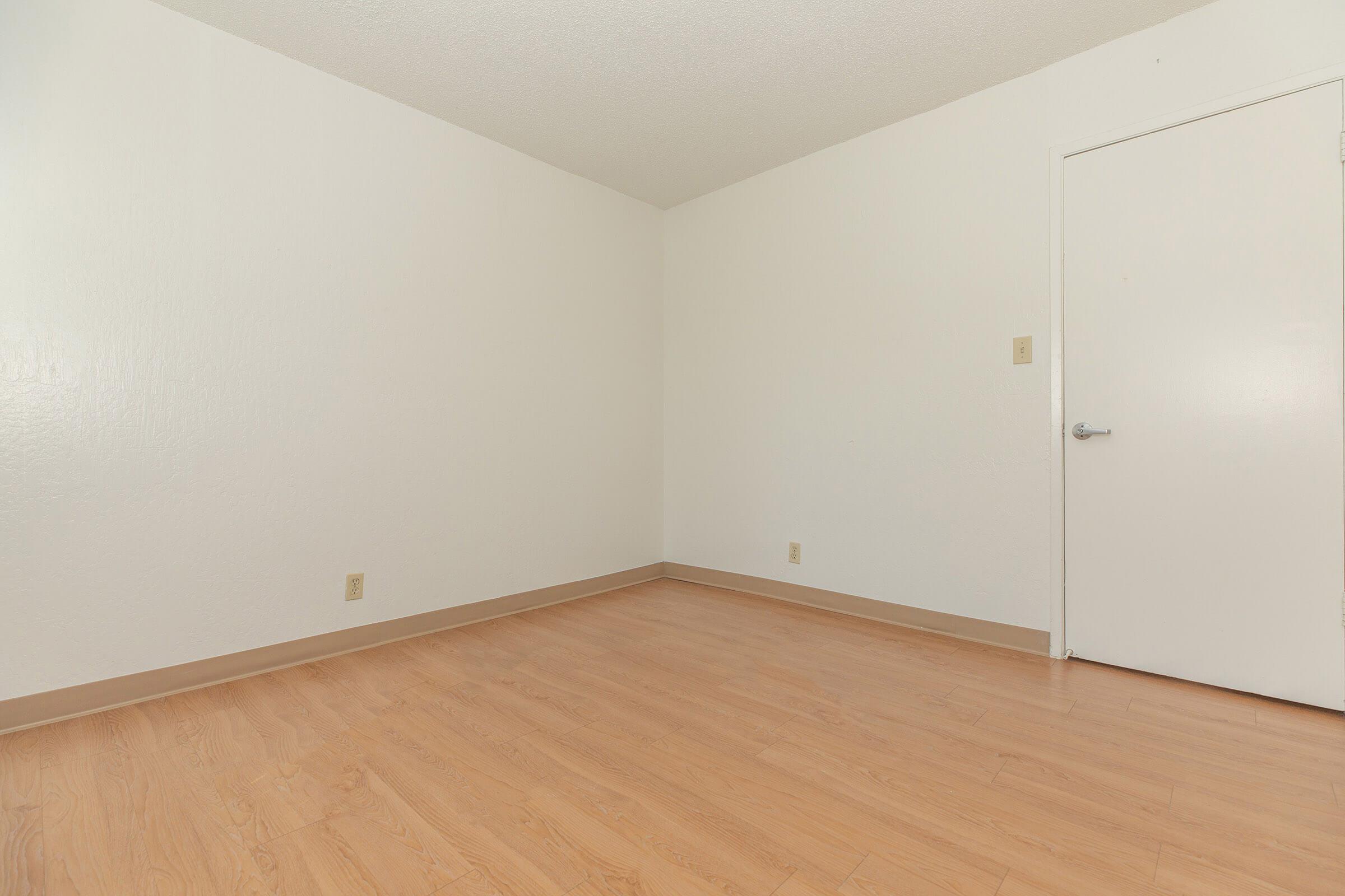 Room door, white walls, and hardwood floors.