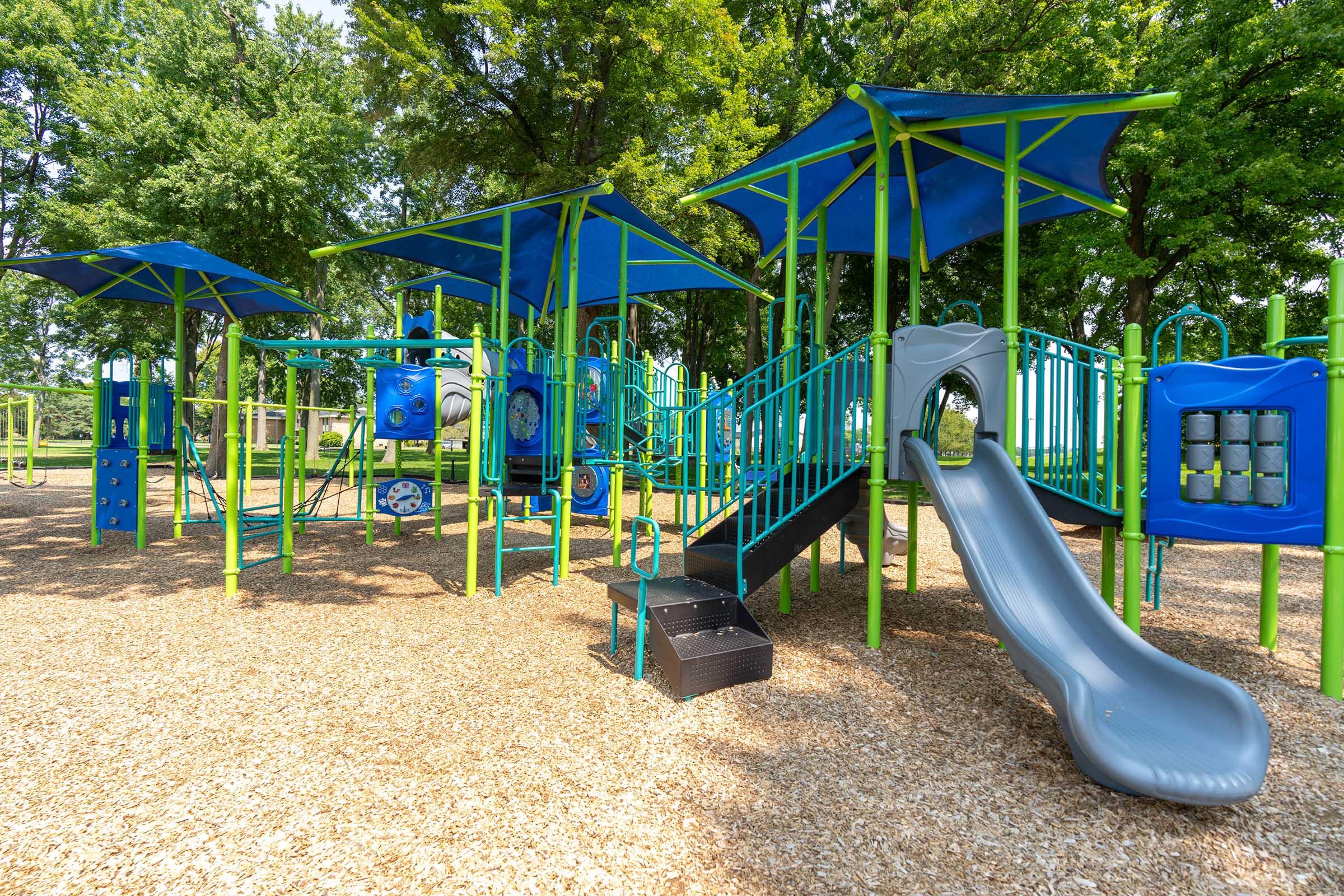 a playground with a blue umbrella