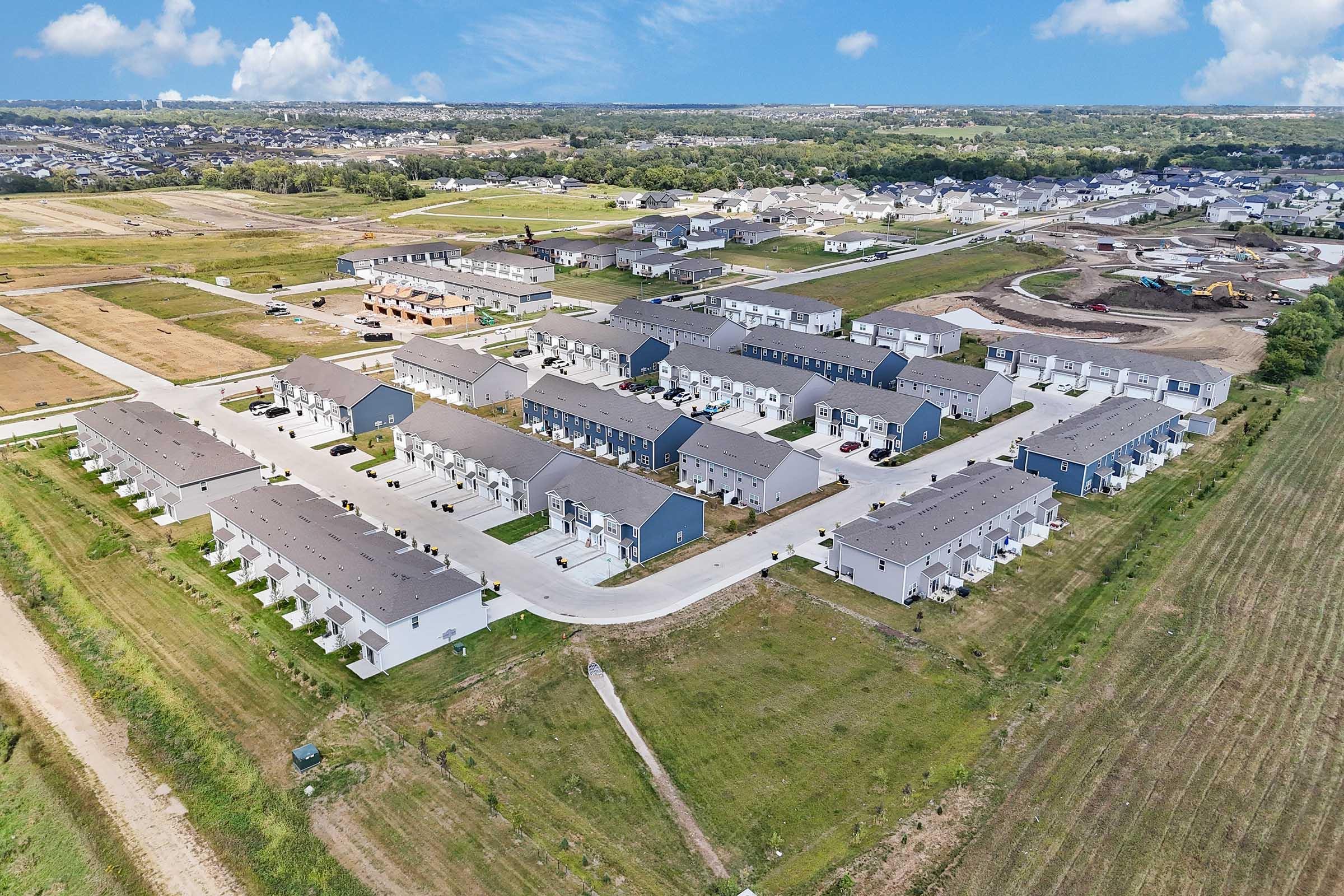Community aerial of Painted Woods Villas showcasing brand-new townhomes with private garages.