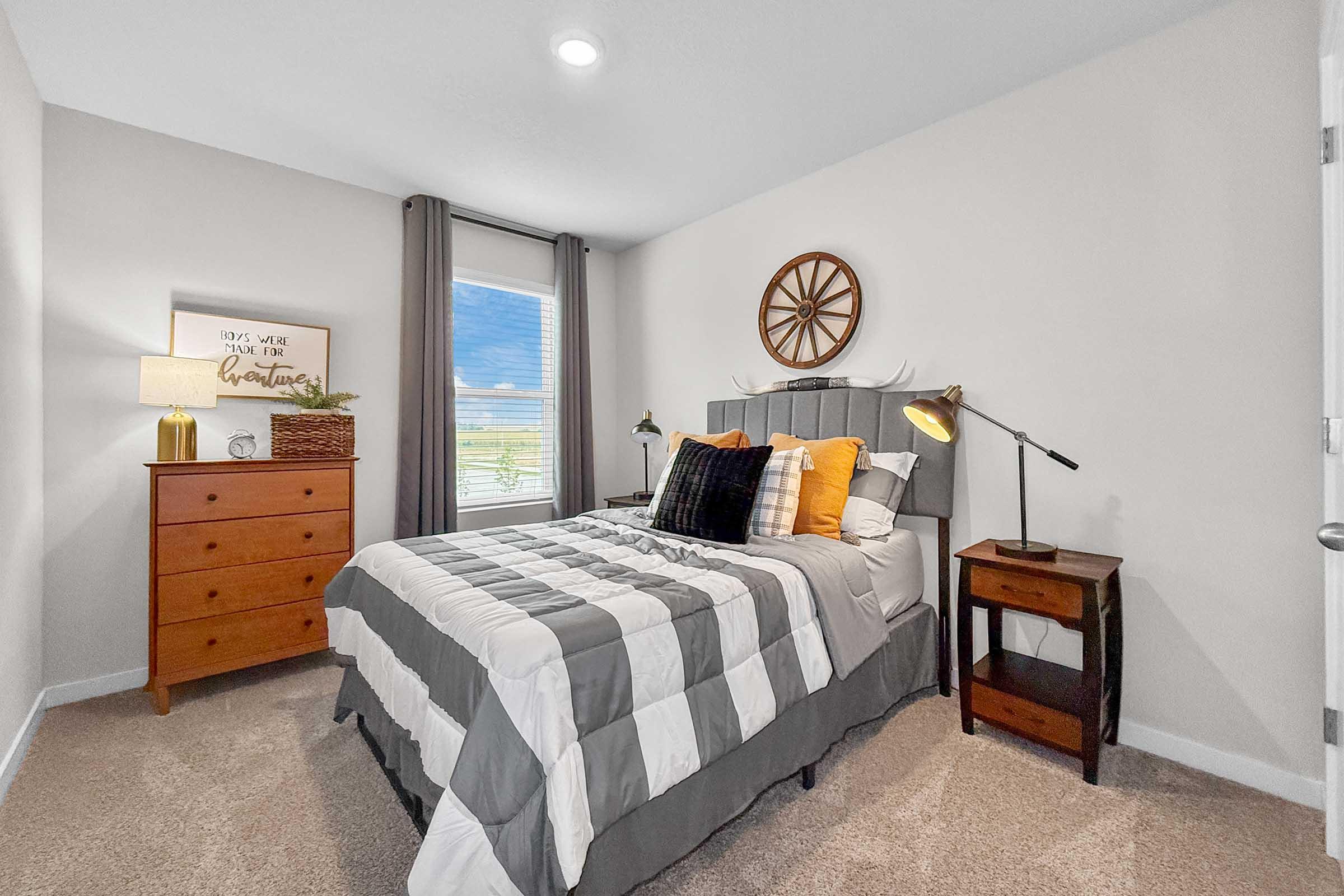 Secondary bedroom with large window and plush carpet in new construction three-bedroom Waukee townhome.