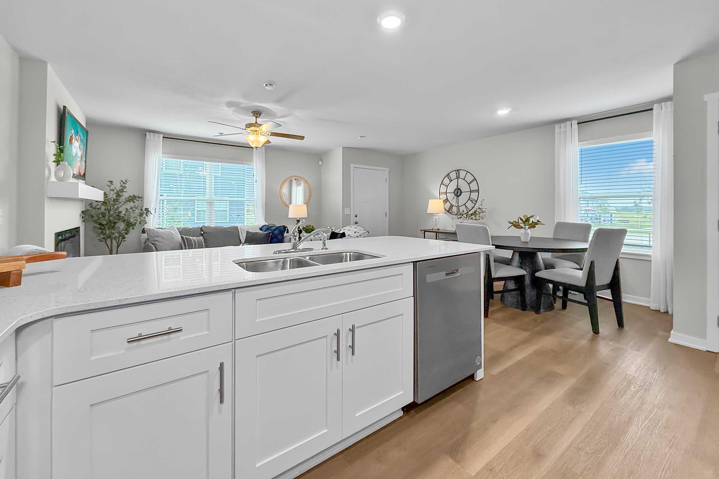 Kitchen island and dining area with quartz countertops in Painted Woods Villas townhome for rent.
