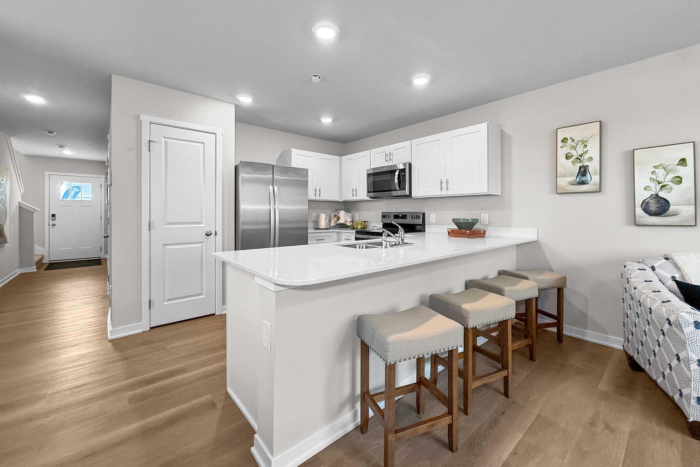 Modern kitchen with stainless steel appliances and breakfast bar in Waukee townhome at Painted Woods Villas.