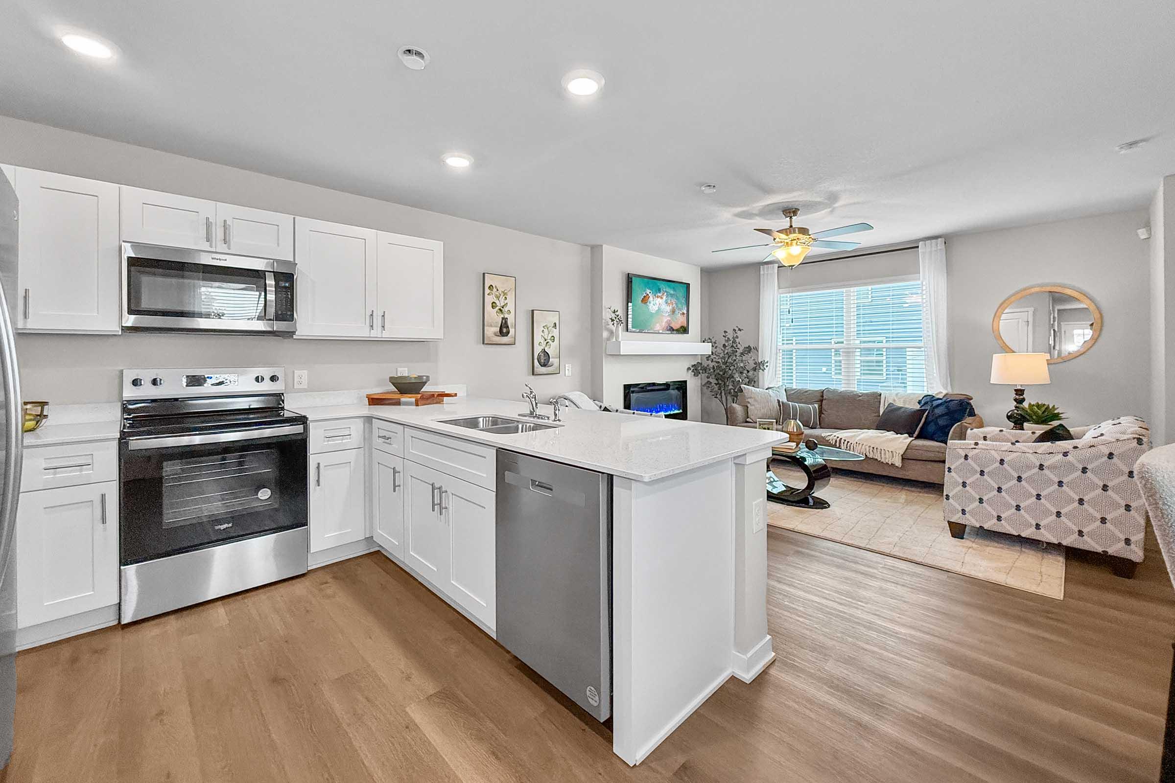 Open kitchen and living space with stainless steel appliances in Painted Woods Villas new townhome.