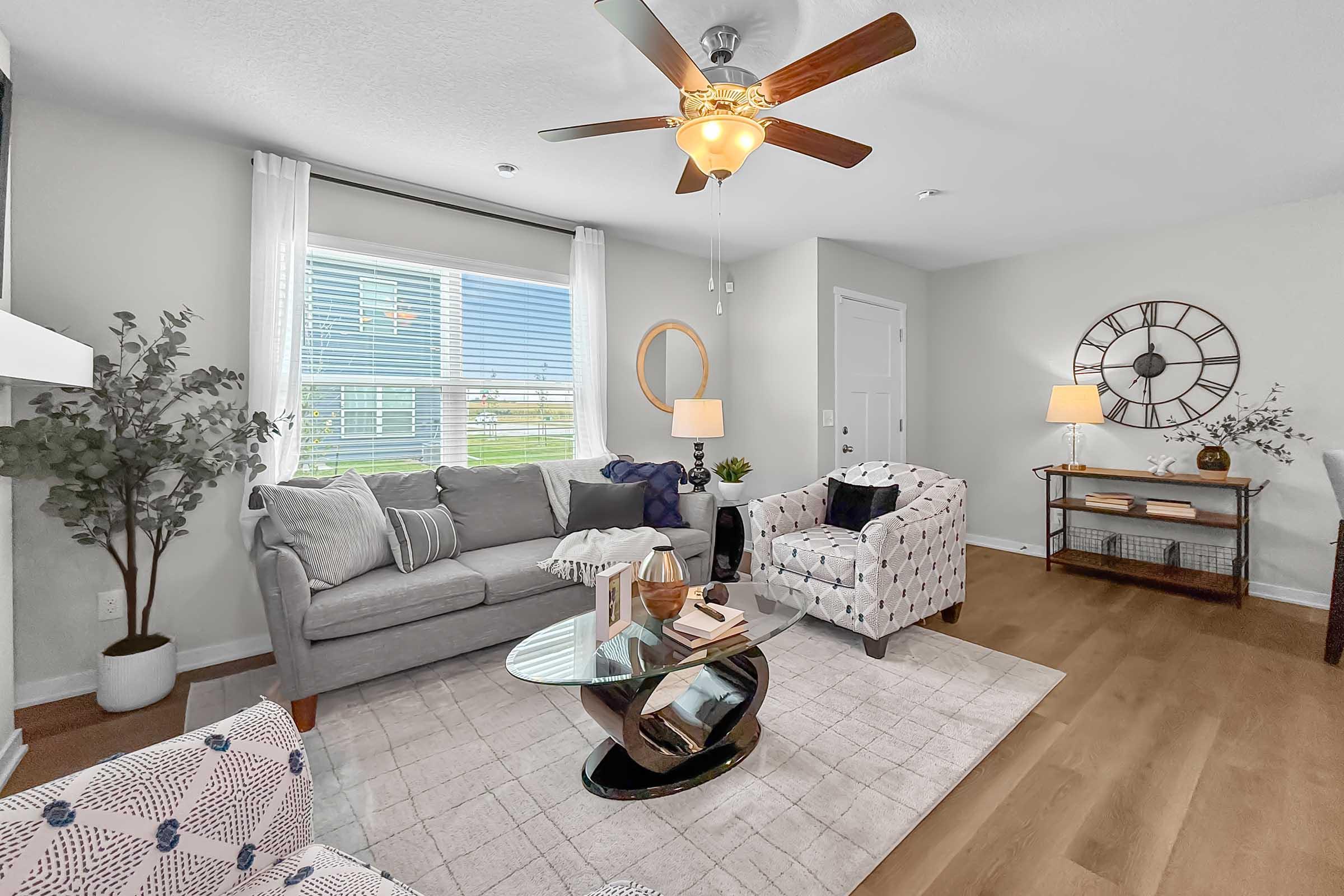 Bright living room with large windows and ceiling fan in Painted Woods Villas new construction townhome.