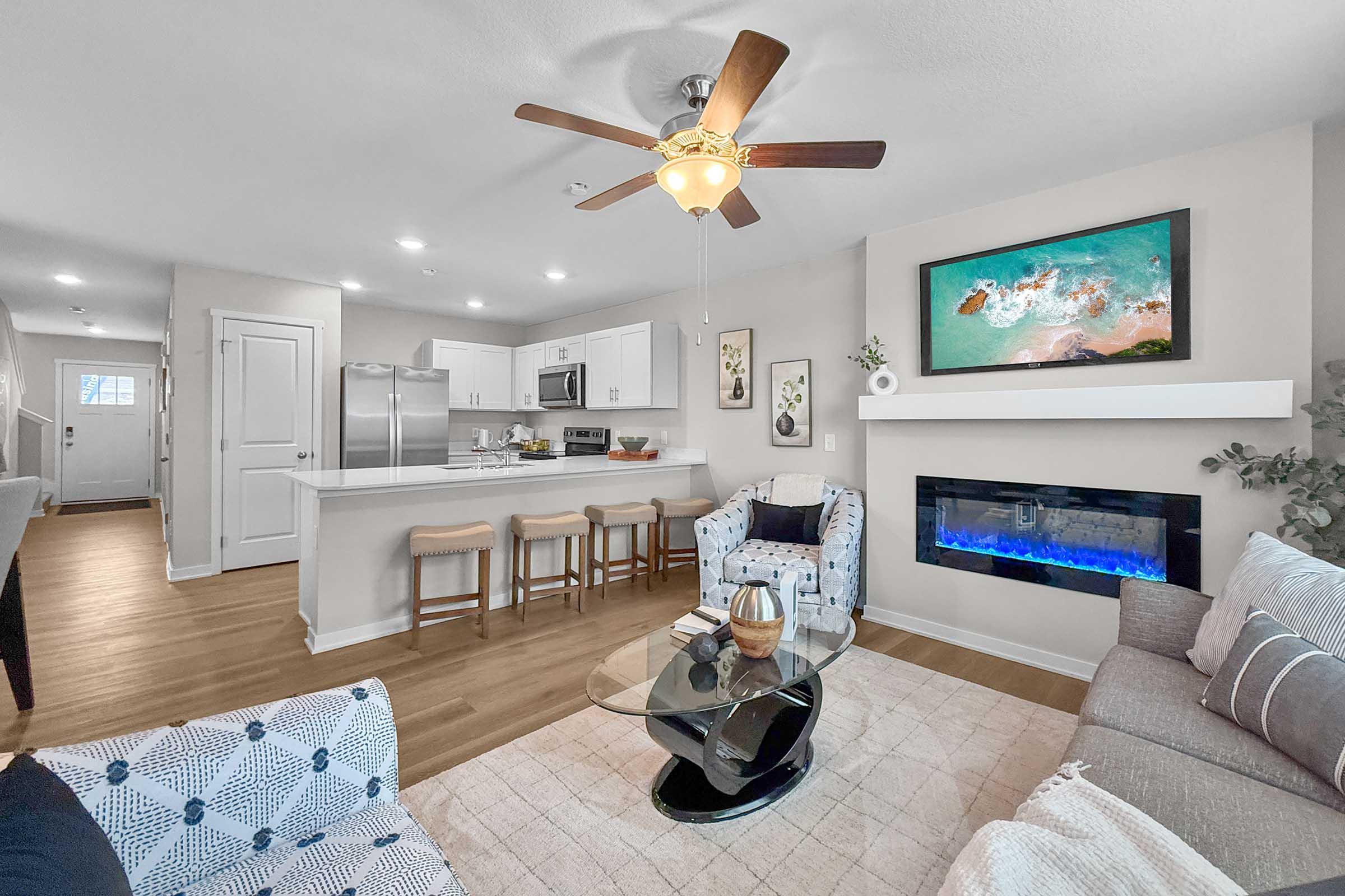 Modern townhome living room with ceiling fan and built-in fireplace at Painted Woods Villas in Waukee.