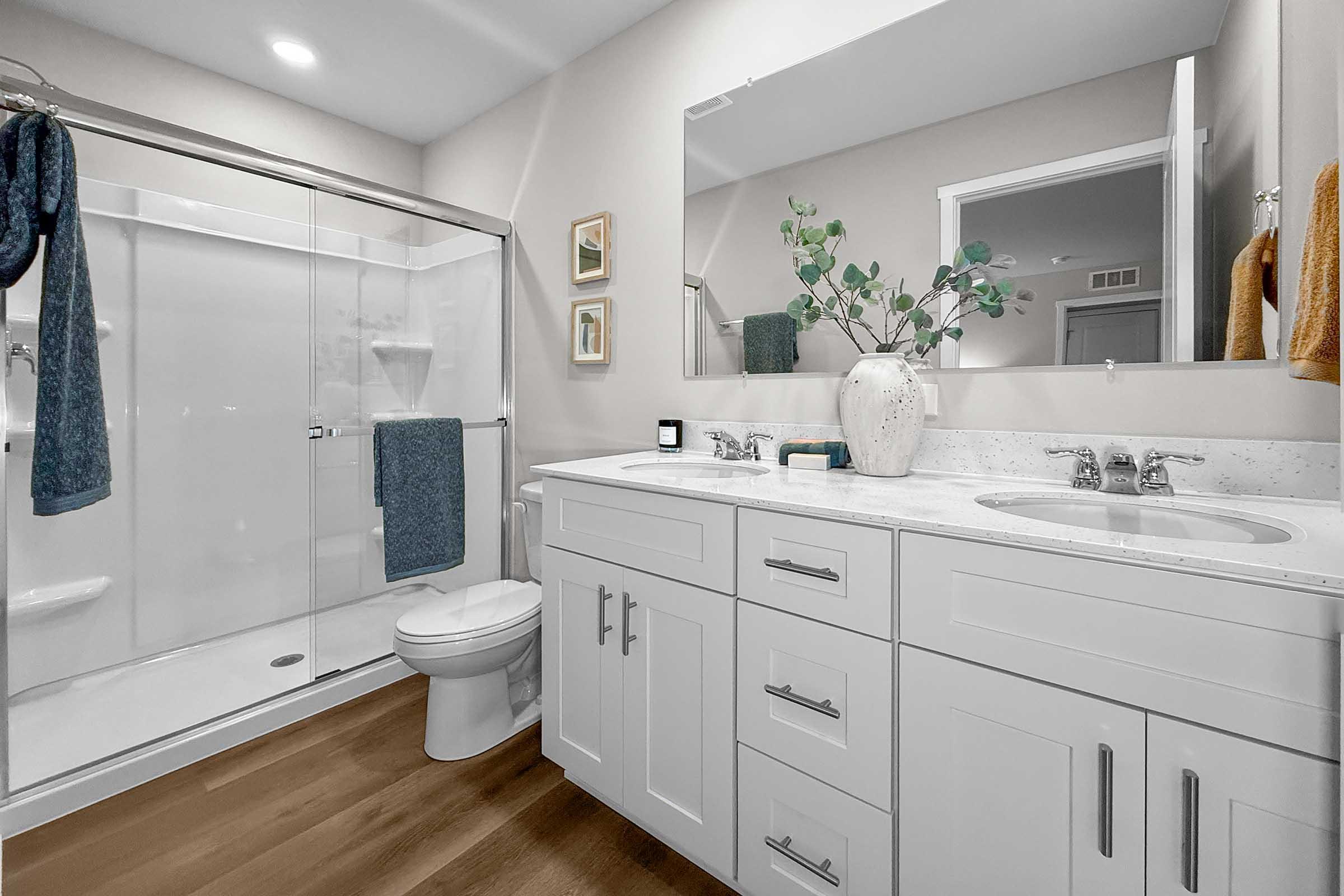 Bathroom with quartz vanity, glass shower, and modern lighting in Painted Woods Villas townhome.