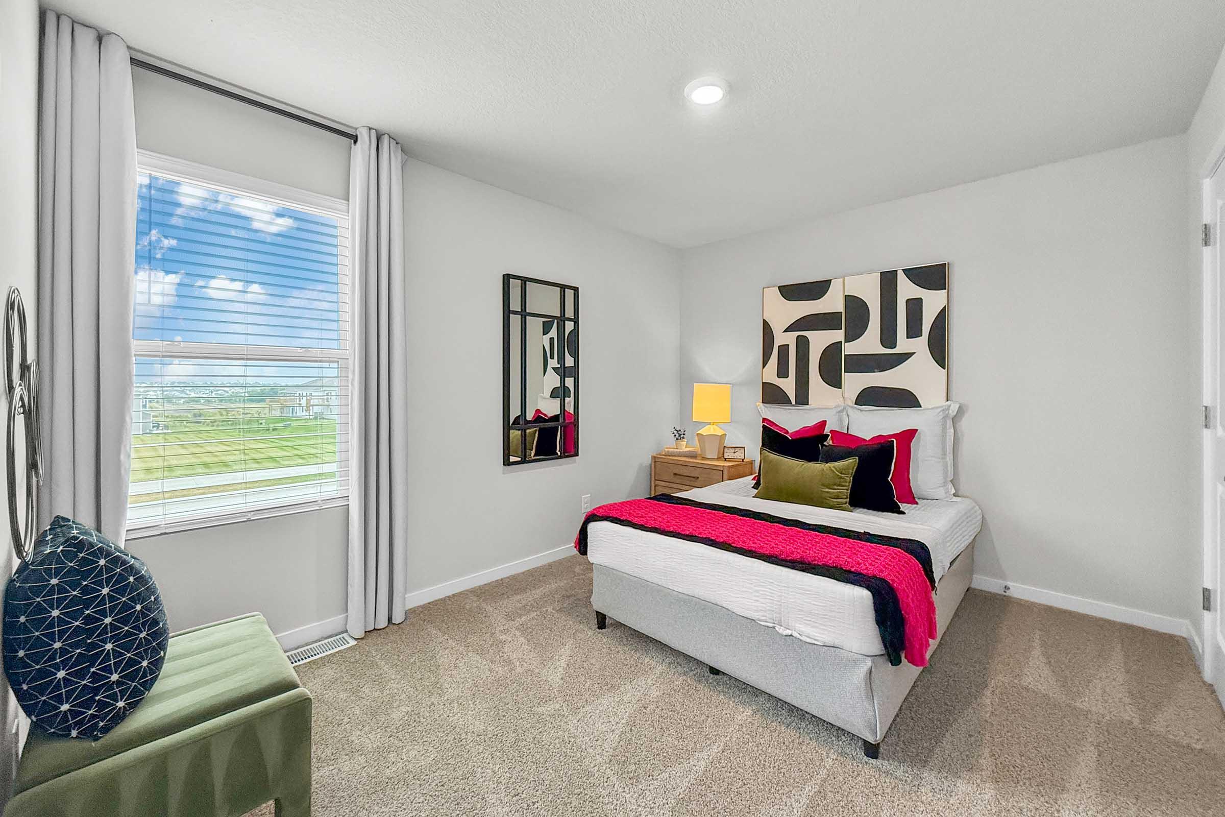 Stylish bedroom with large window and plush carpet in Painted Woods Villas three-bedroom townhome.