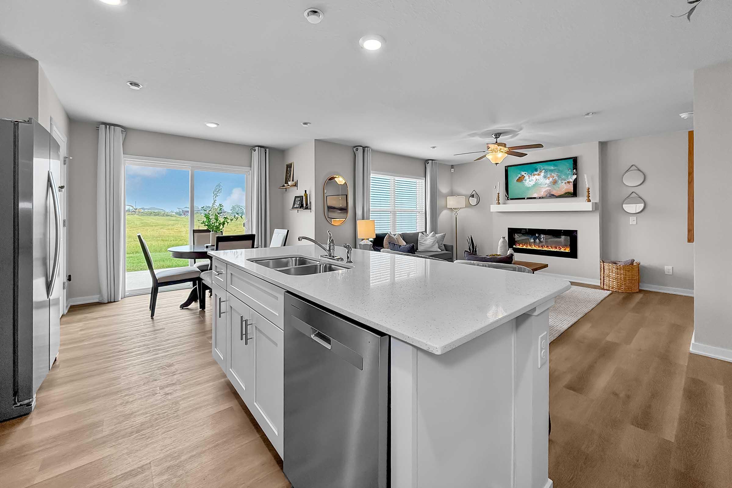 Open kitchen and dining area with quartz countertops and natural light in Waukee townhome.
