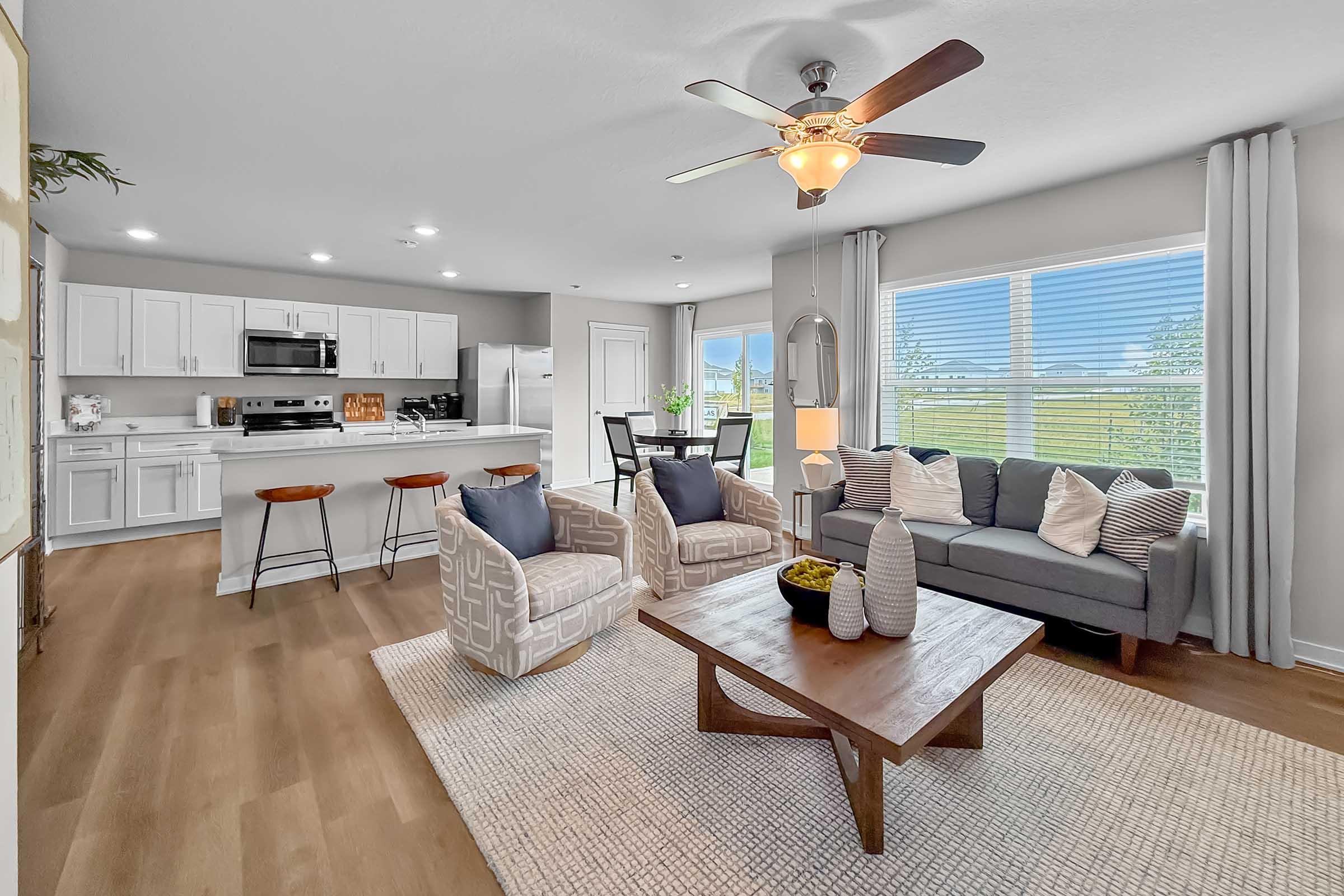 Bright family room with large windows and dining space in Painted Woods Villas townhome for rent.
