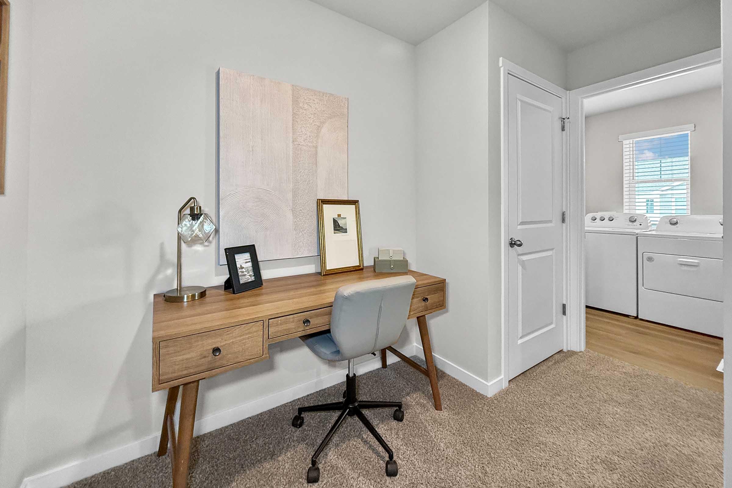 Bedroom staged as home office with carpet and window light in Painted Woods Villas townhome.