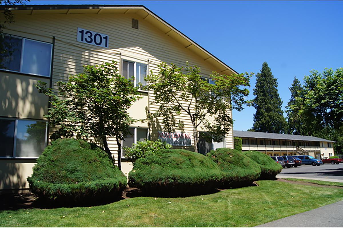 a large brick building with green grass in front of a house