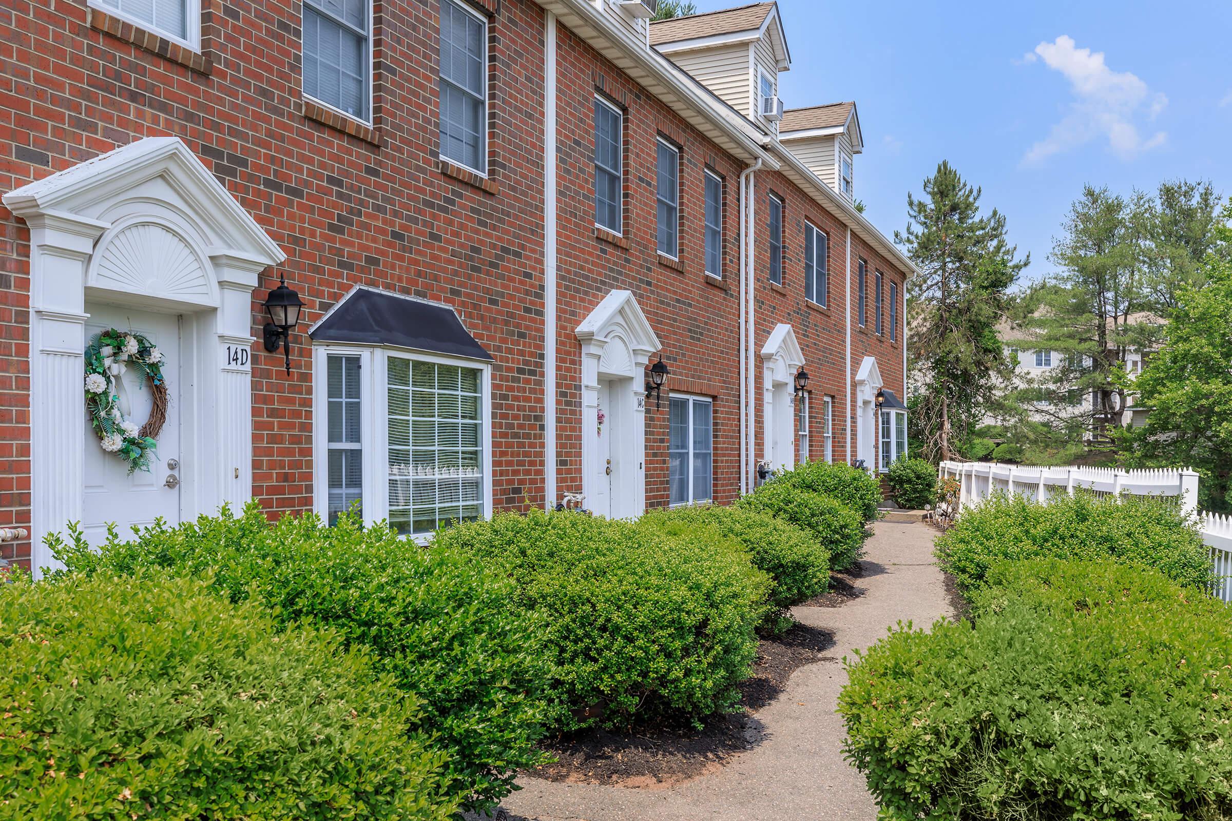 a house with bushes in front of a brick building