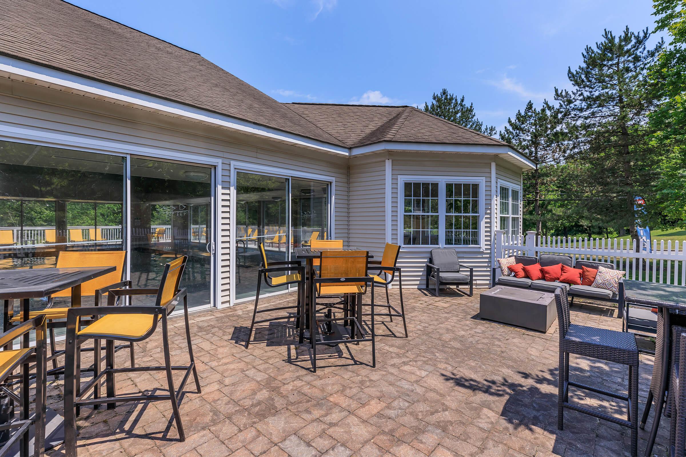 Manchester, CT Apartments for Rent - The Manchester - Patio with outdoor Furniture, Lush Landscaping, and Brick Laid Flooring