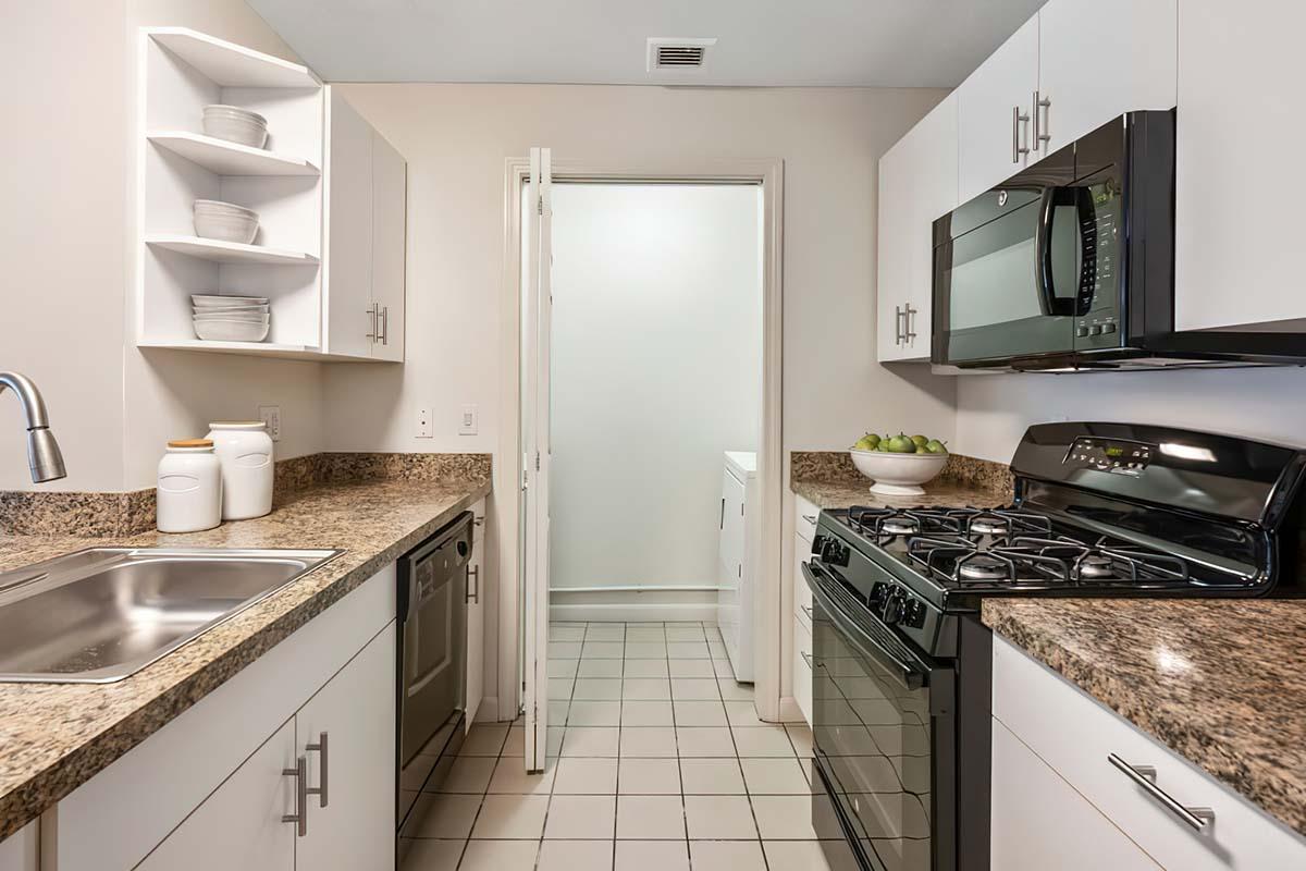 One-Bedroom Apartments in Manchester, CT - The Manchester - Kitchen with Tile Flooring, Open Shelving, and Black Essential Kitchen Appliances