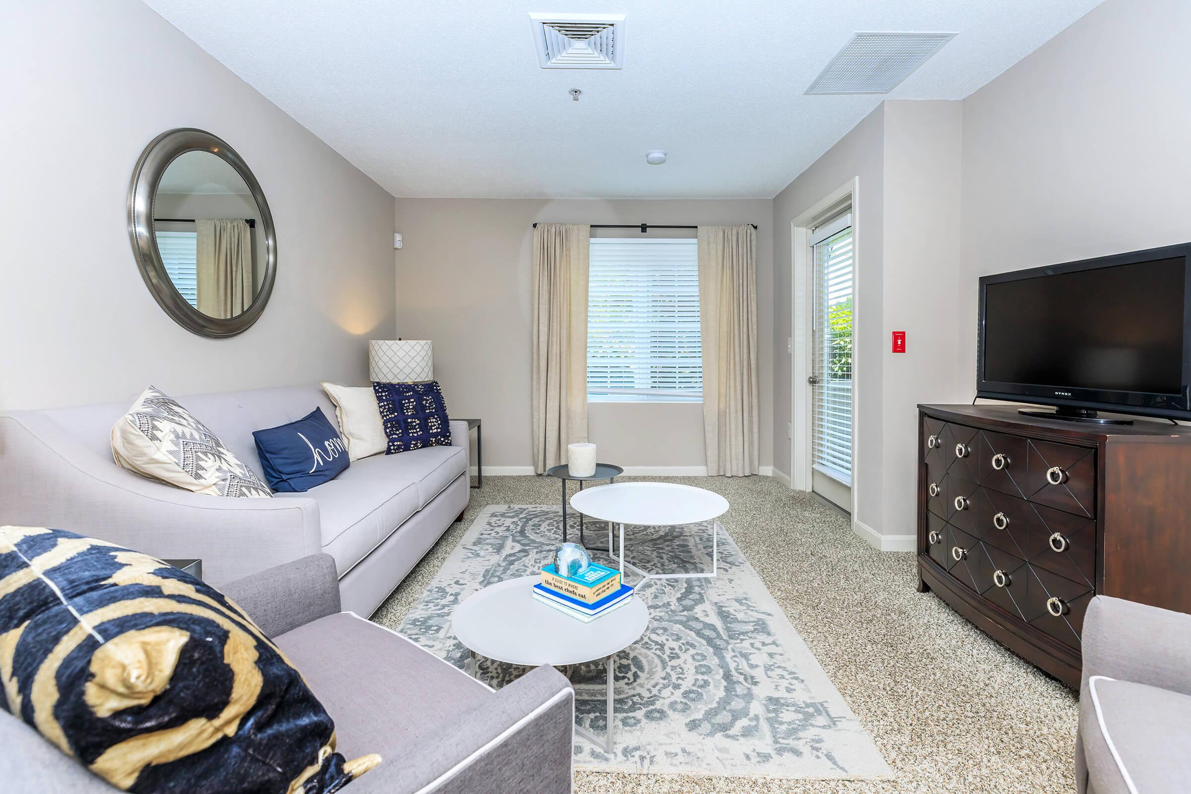 Apartments Near Hartford - The Manchester - Living Room with Carpeting, Entrance to a Private Patio, and Grey Furniture